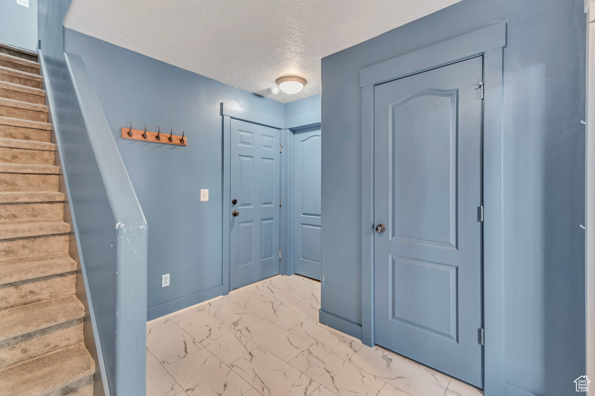 Doorway to outside with marble finish floor, a textured ceiling, baseboards, and stairs