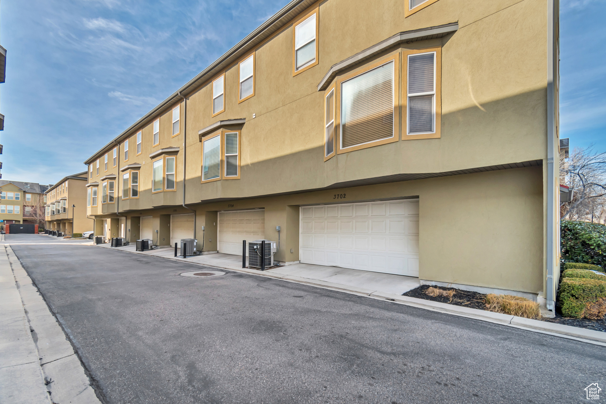 View of property with a garage, central AC unit, and a residential view