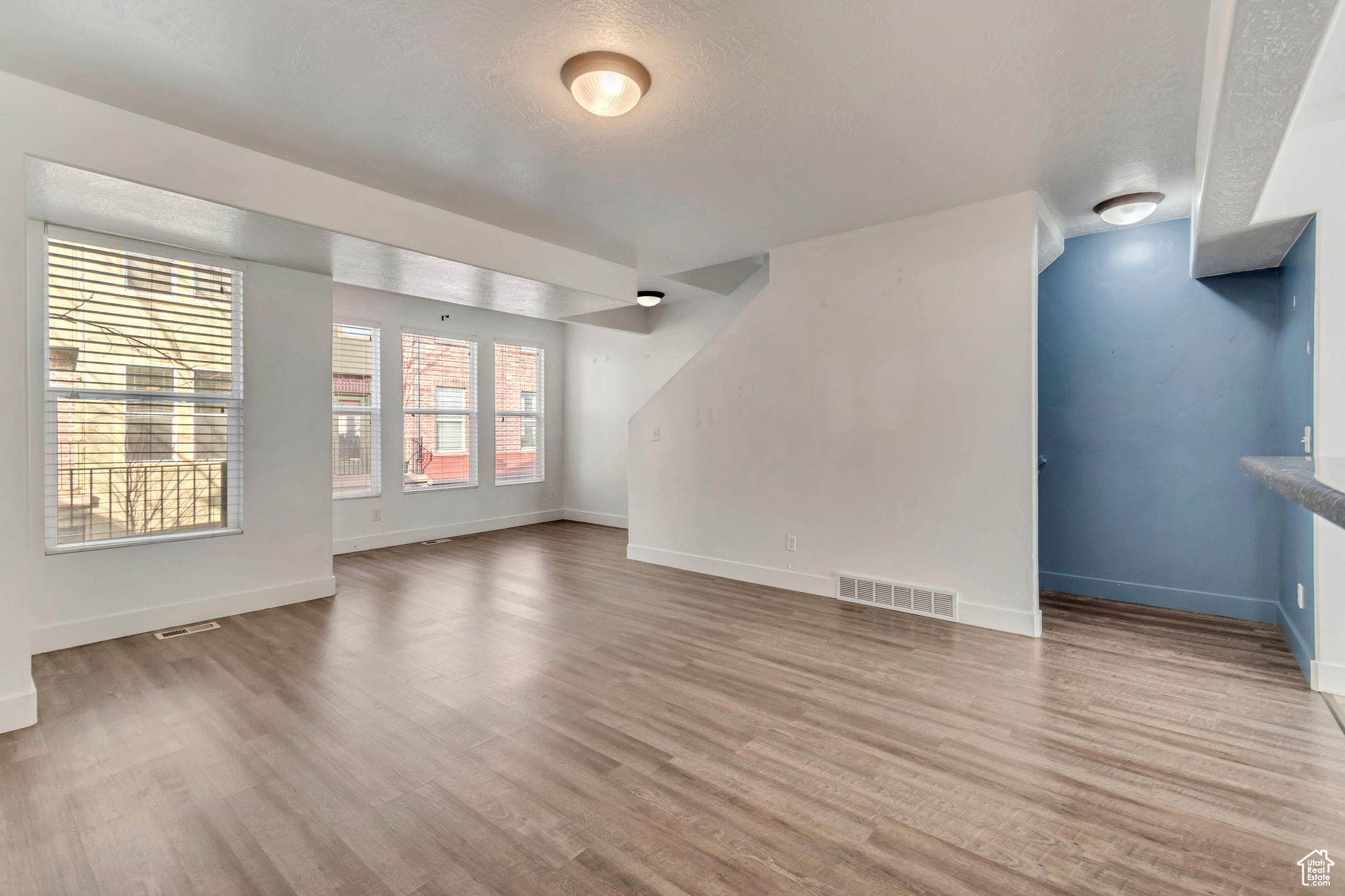 Empty room with light wood-style floors, baseboards, and visible vents
