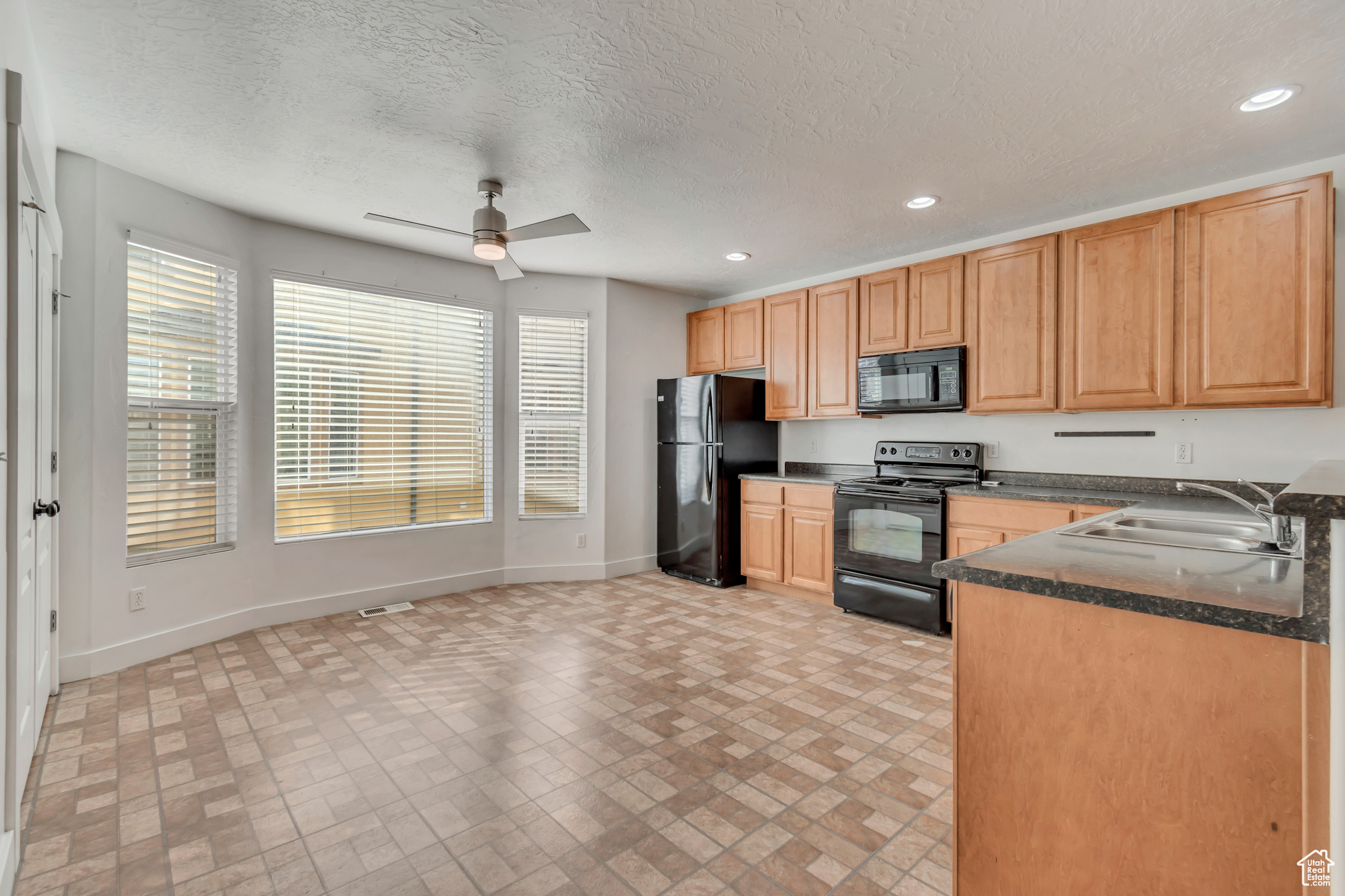 Kitchen with dark countertops, baseboards, black appliances, and recessed lighting