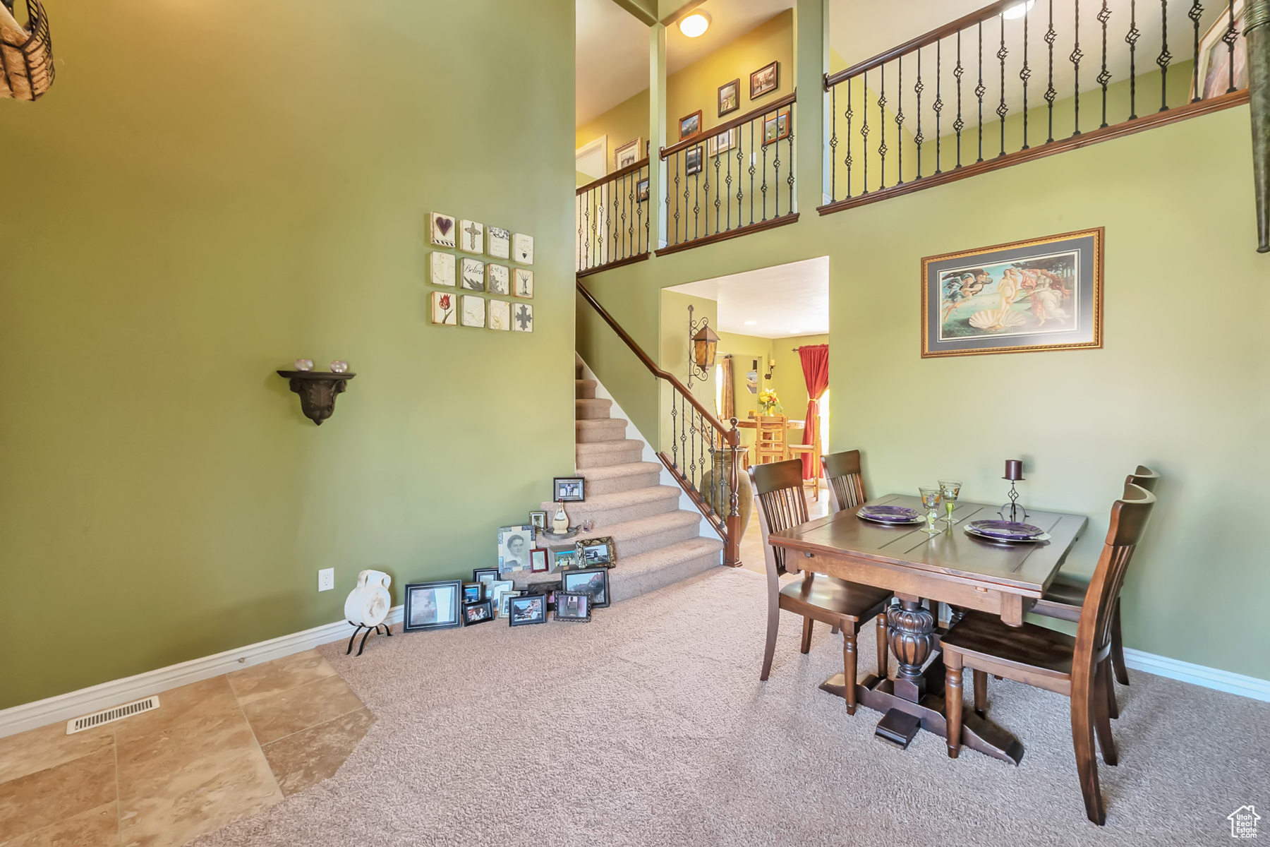Dining space featuring carpet flooring, a towering ceiling, visible vents, baseboards, and stairway