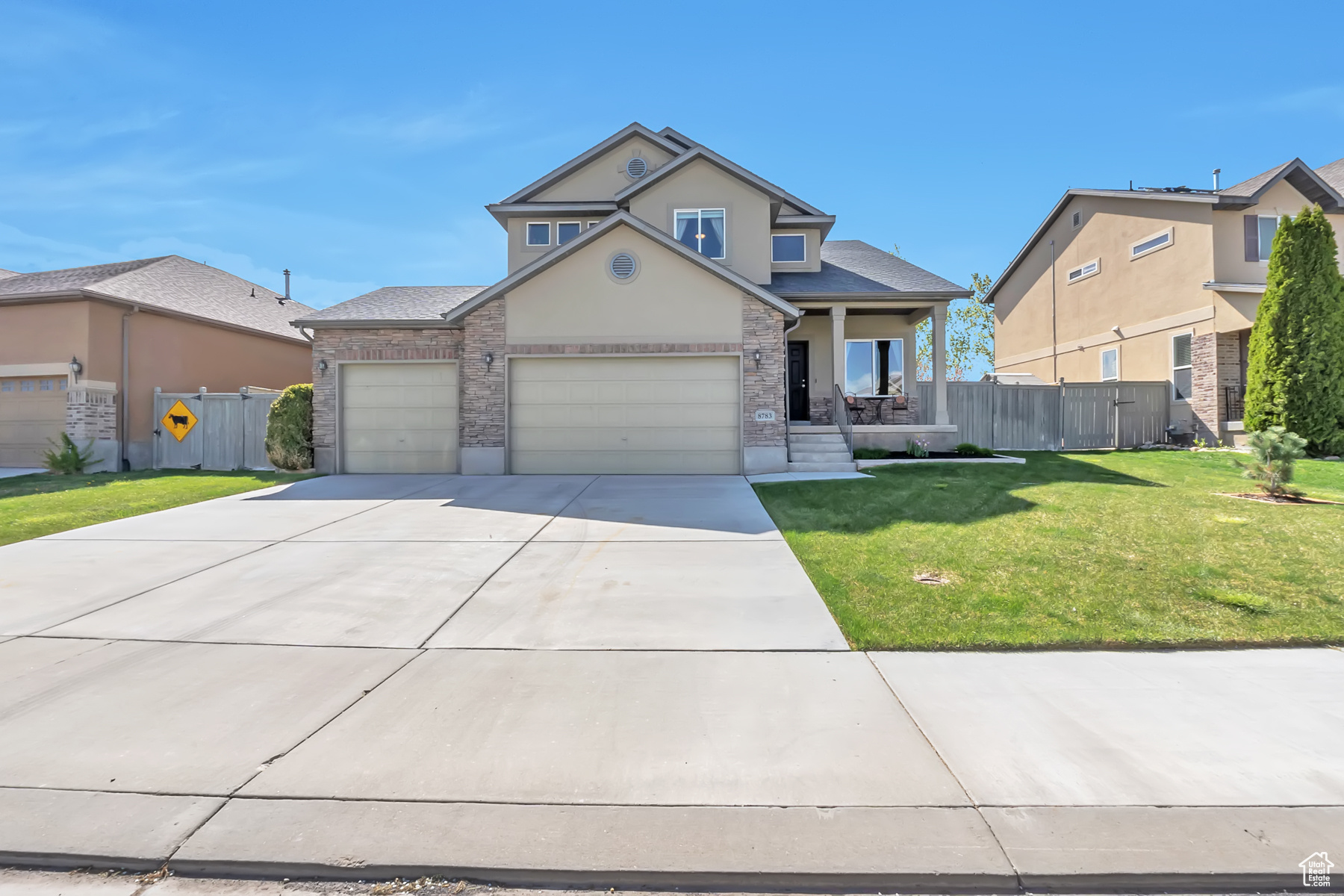 Traditional home with driveway, stucco siding, covered porch, fence, and a front yard