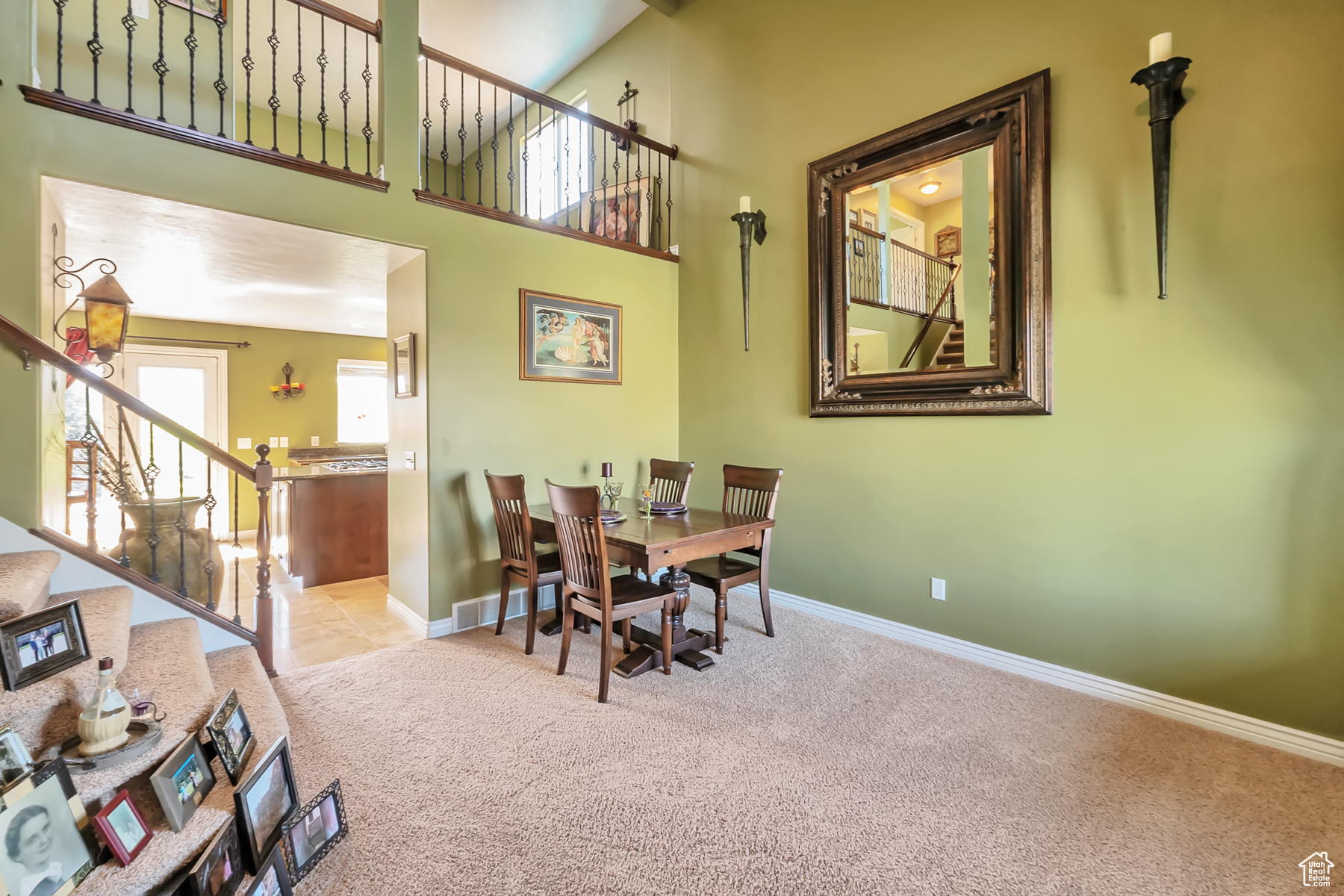 Dining room with light carpet, a high ceiling, visible vents, baseboards, and stairway