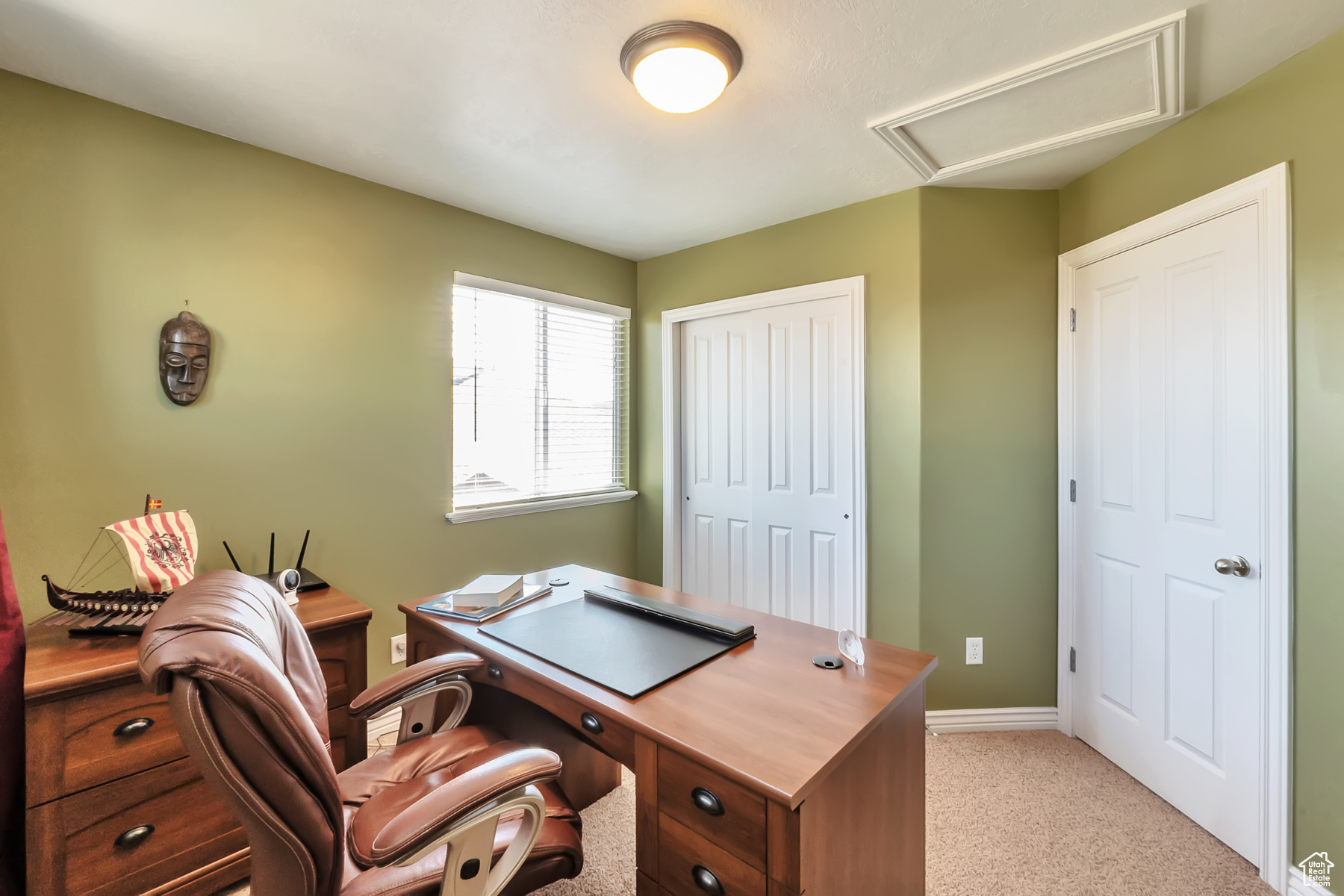 Home office featuring light carpet, attic access, and baseboards