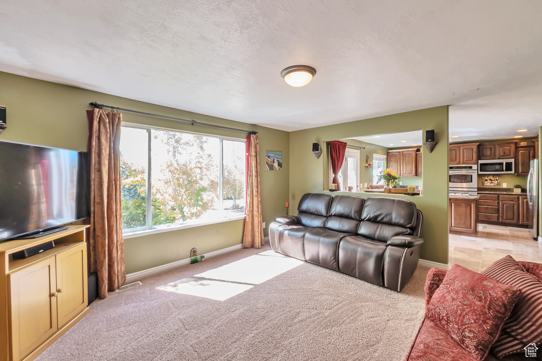 Living area with light carpet, a textured ceiling, and baseboards