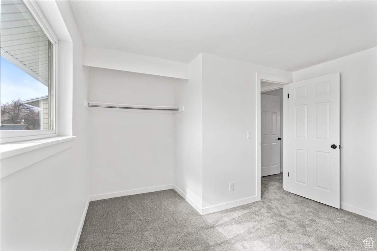 Unfurnished bedroom with light carpet, a closet, and baseboards
