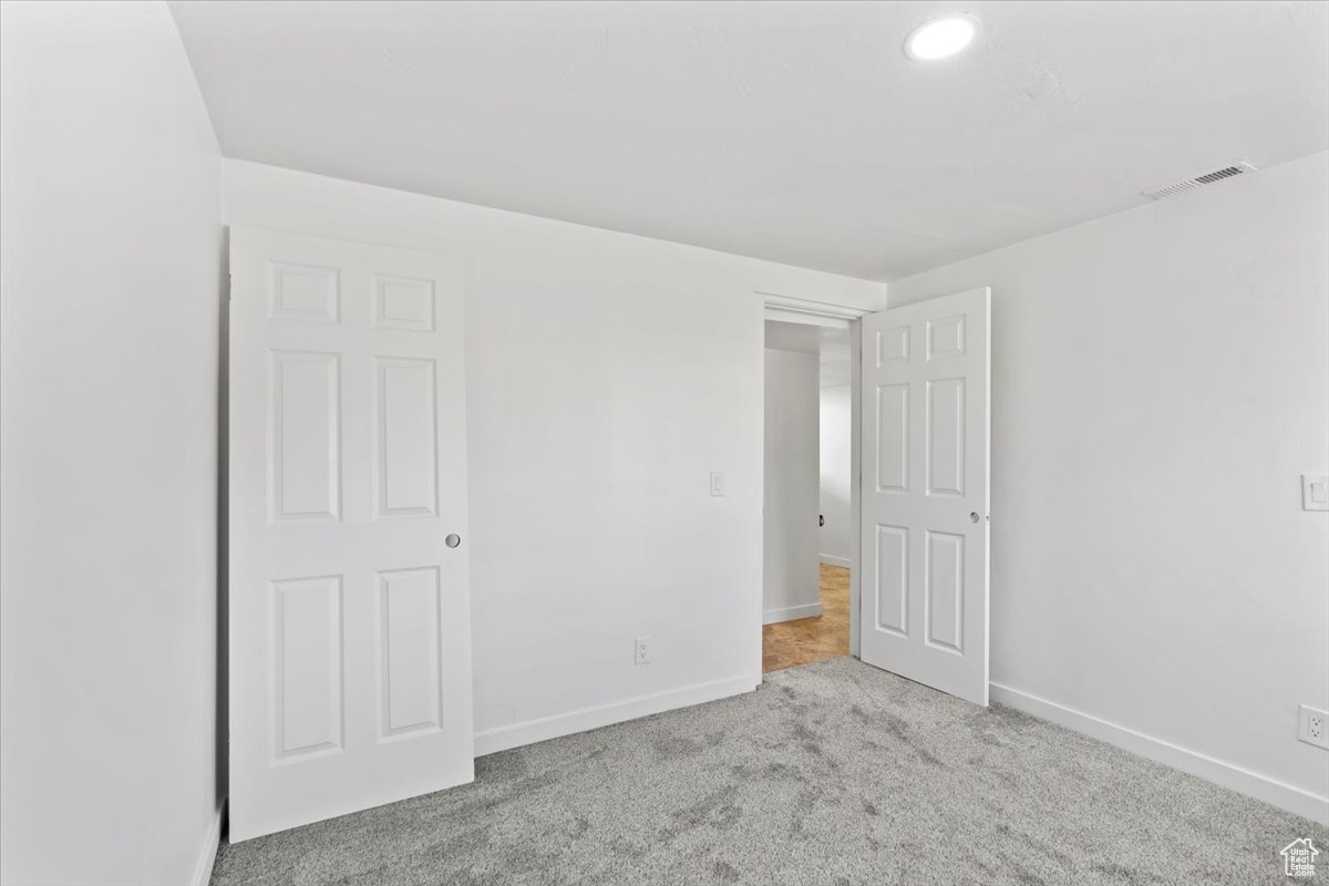 Unfurnished bedroom with light colored carpet, visible vents, and baseboards