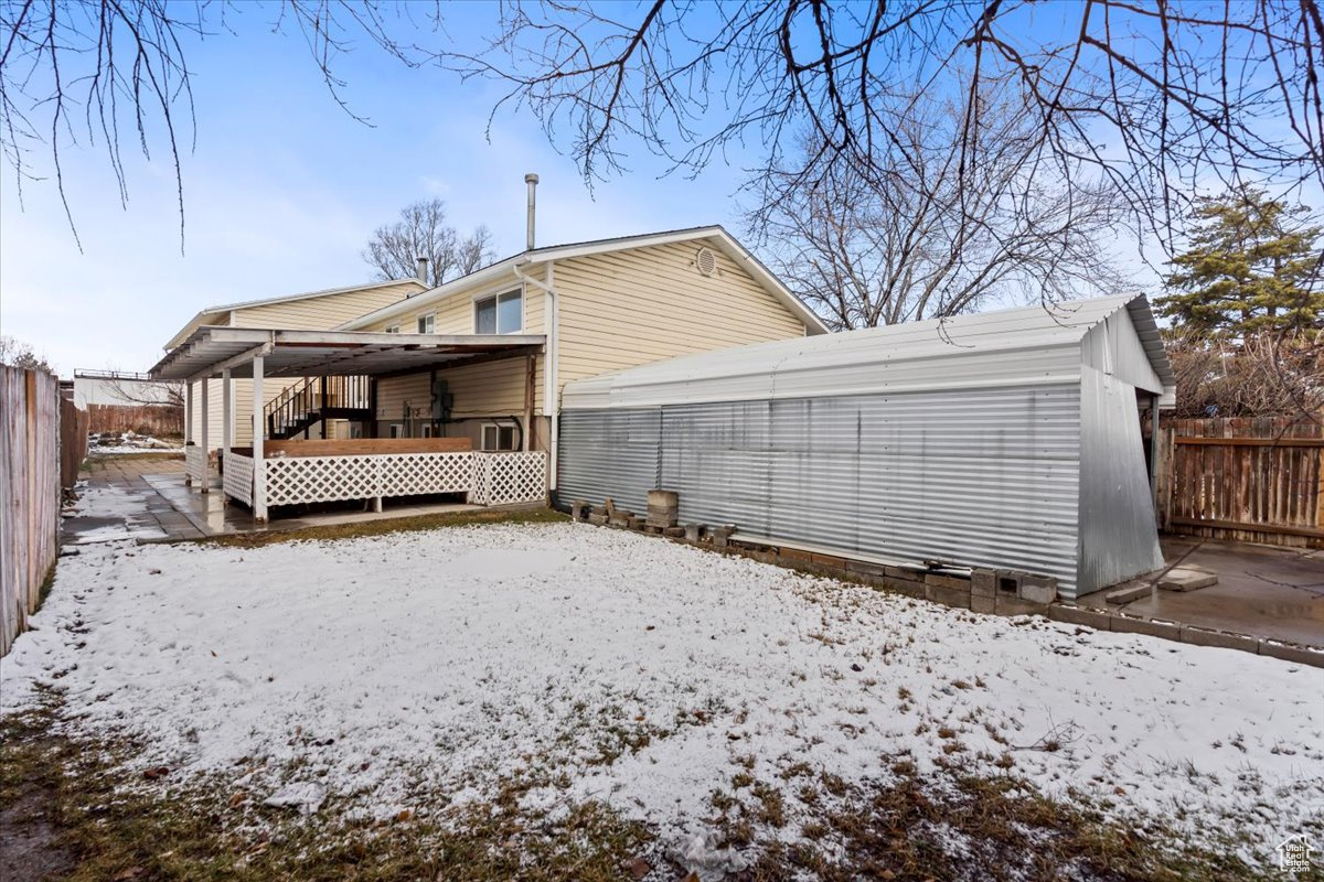 Snow covered rear of property featuring fence