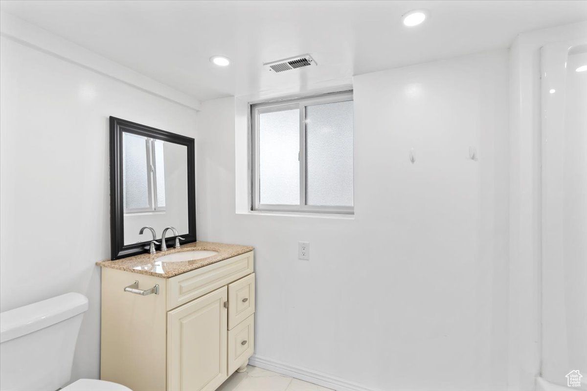 Half bathroom featuring visible vents, baseboards, toilet, vanity, and recessed lighting