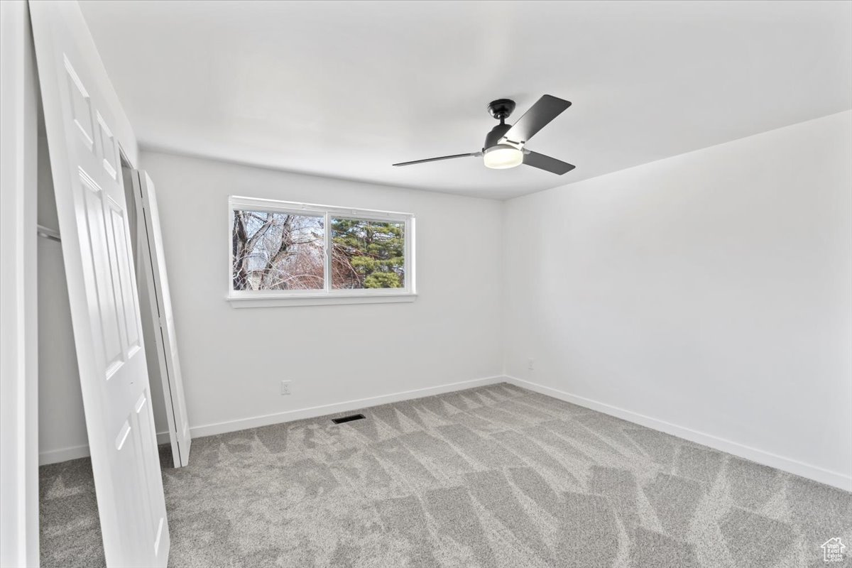 Unfurnished bedroom featuring light carpet, ceiling fan, visible vents, and baseboards