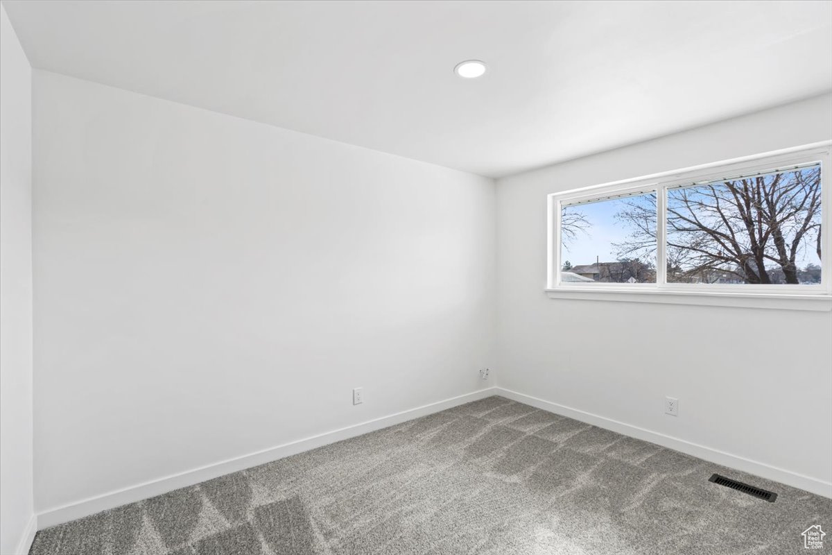 Carpeted empty room featuring recessed lighting, visible vents, and baseboards