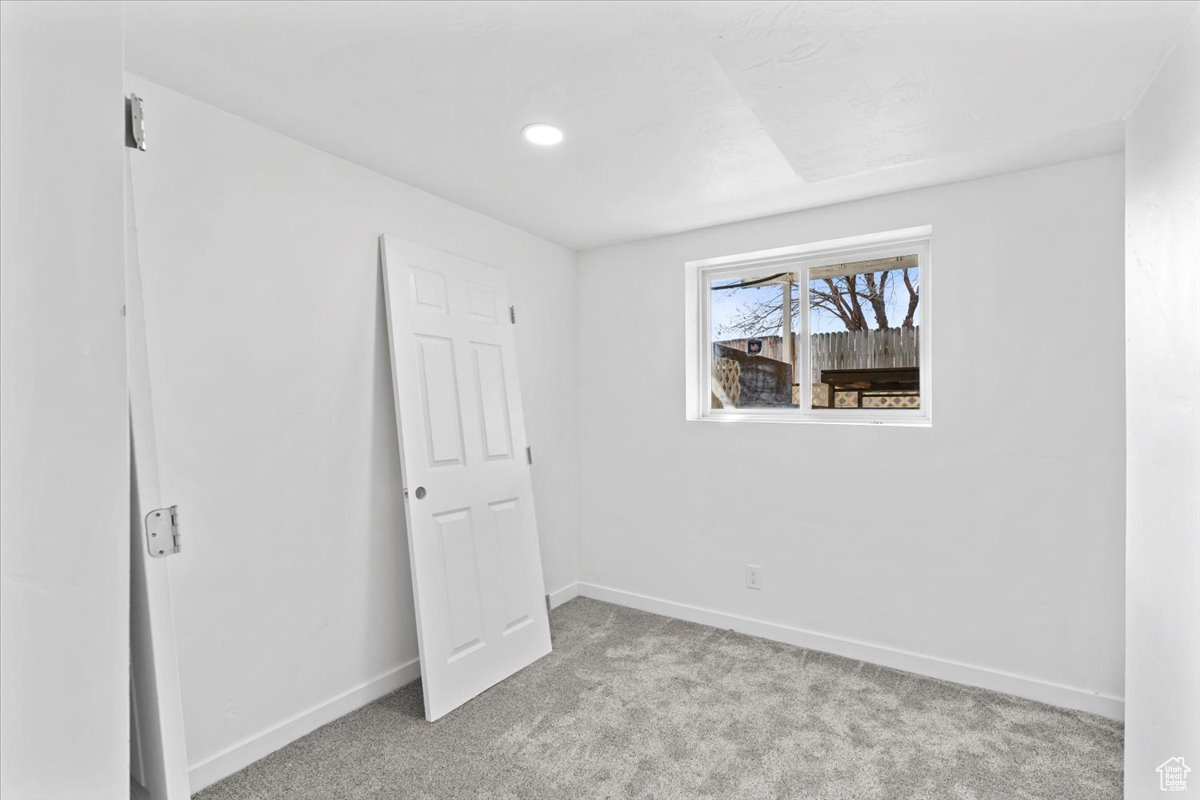 Unfurnished bedroom with light carpet and baseboards
