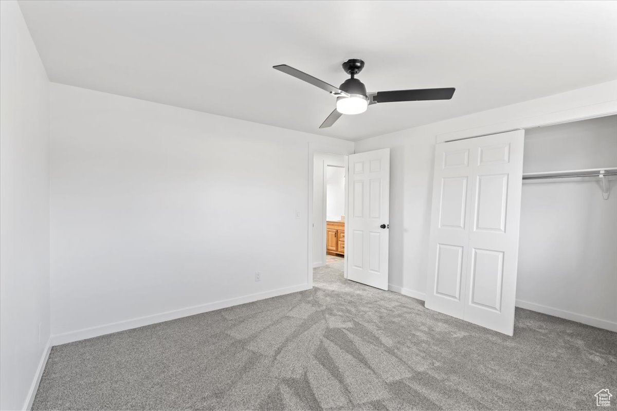 Unfurnished bedroom with carpet, baseboards, ceiling fan, and a closet