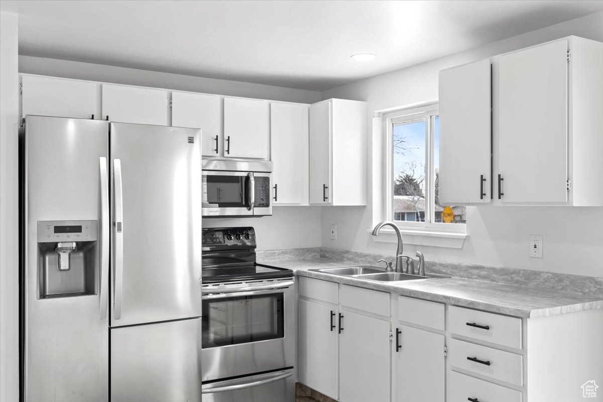 Kitchen featuring a sink, white cabinetry, stainless steel appliances, and light countertops