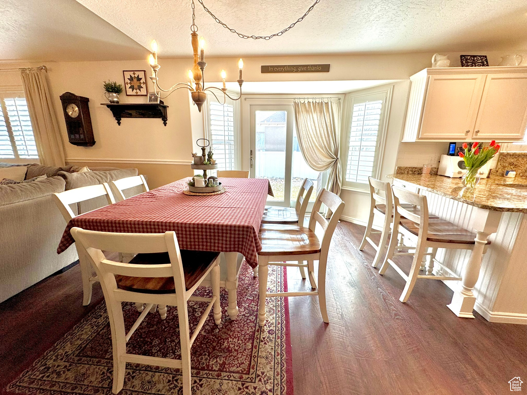 Dining area featuring dark wood-type flooring, a chandelier, a textured ceiling, and baseboards