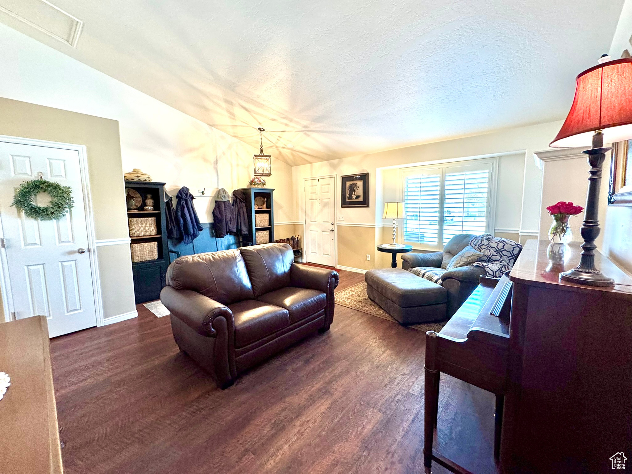 Living room with a textured ceiling, dark wood finished floors, and baseboards