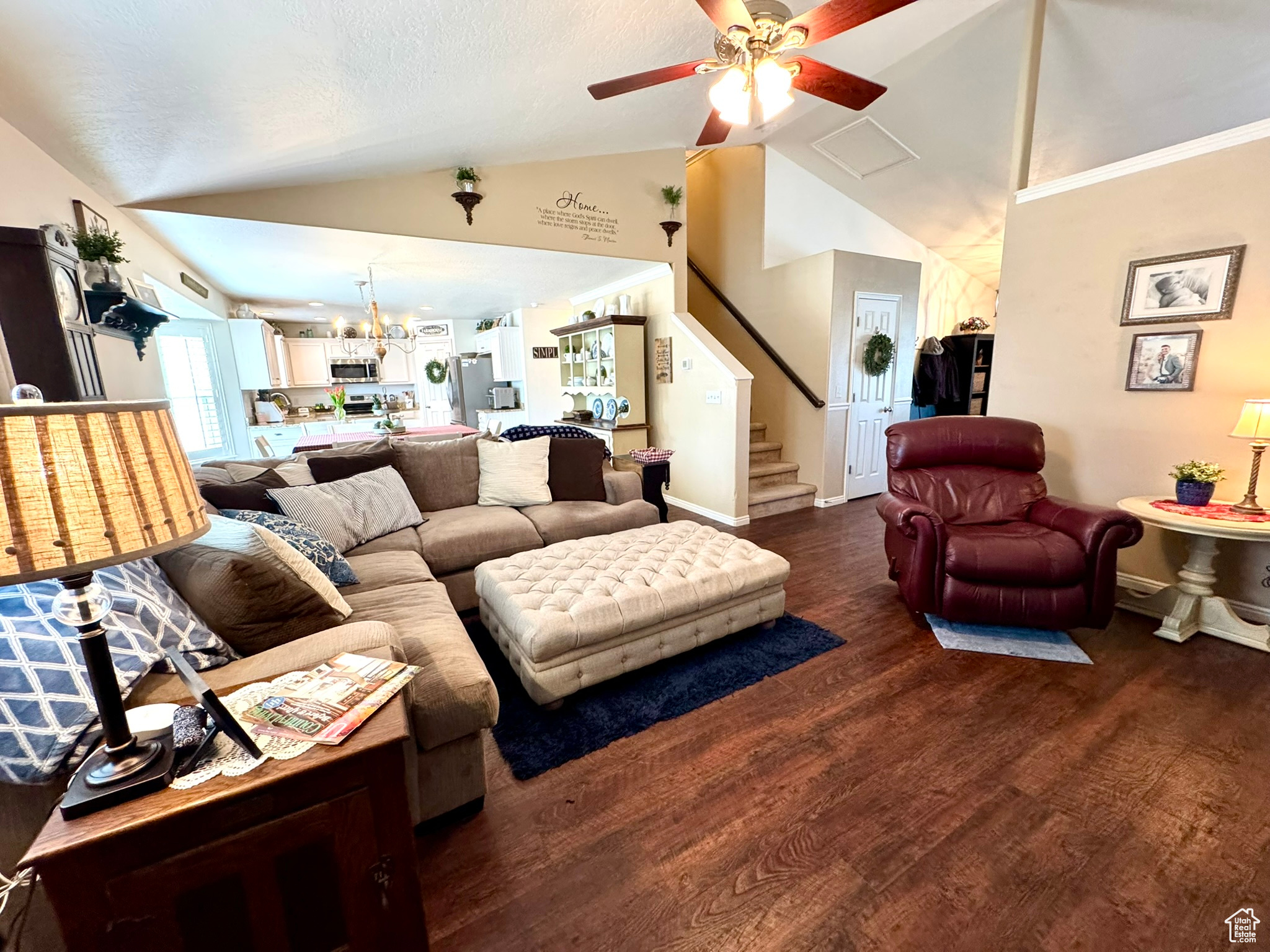 Great room with baseboards, dark wood finished floors, a ceiling fan, stairs, and vaulted ceiling
