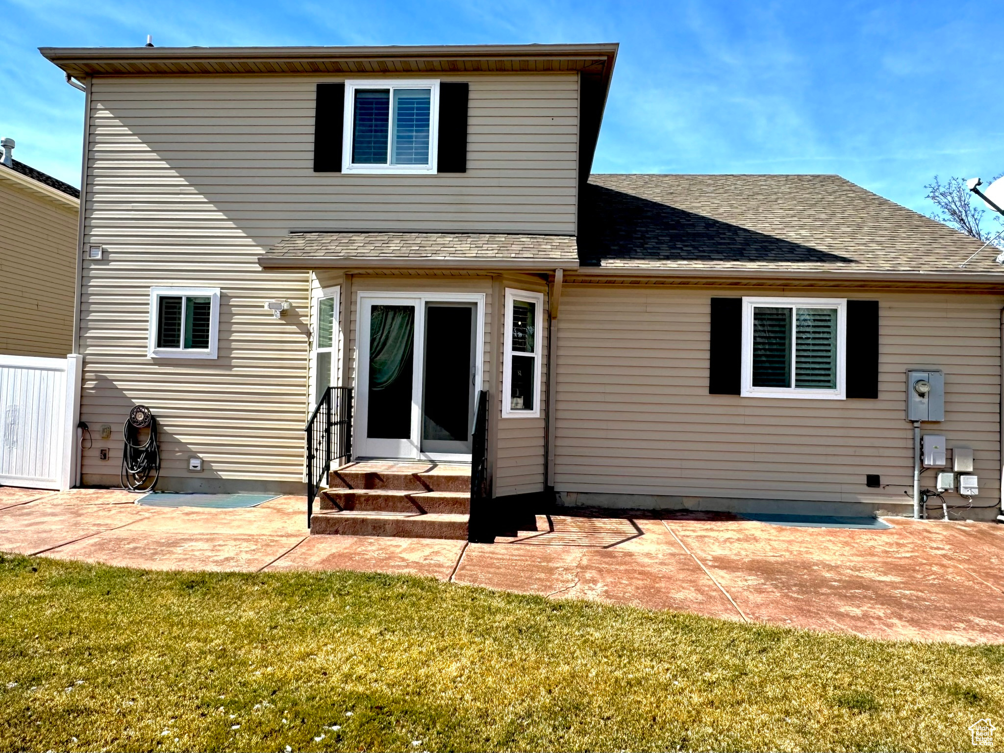 Rear view of property featuring a shingled roof, entry steps, a patio area, and a yard