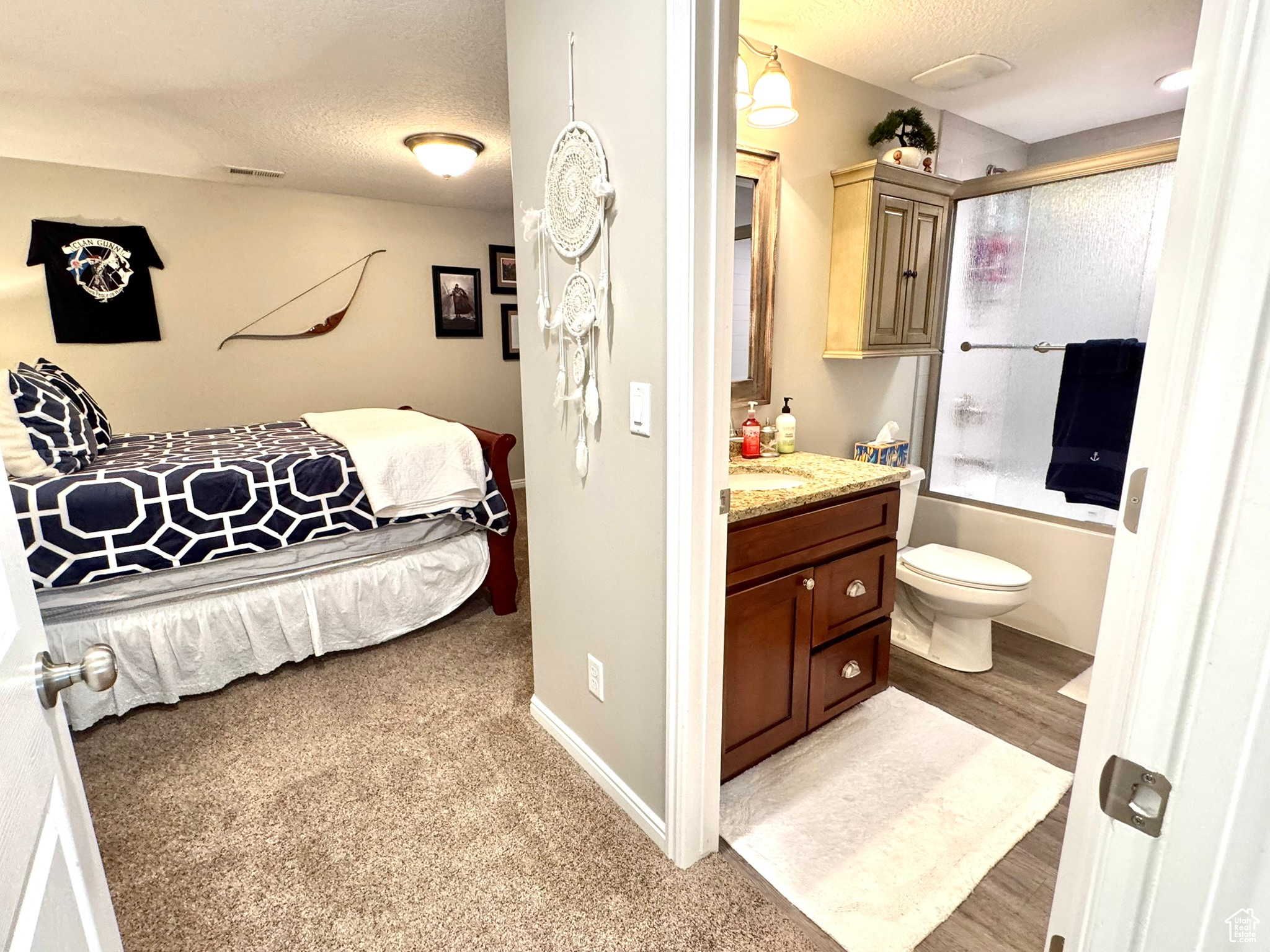 Bedroom 4 with a textured ceiling, connected bathroom, light wood-style flooring, visible vents, and baseboards