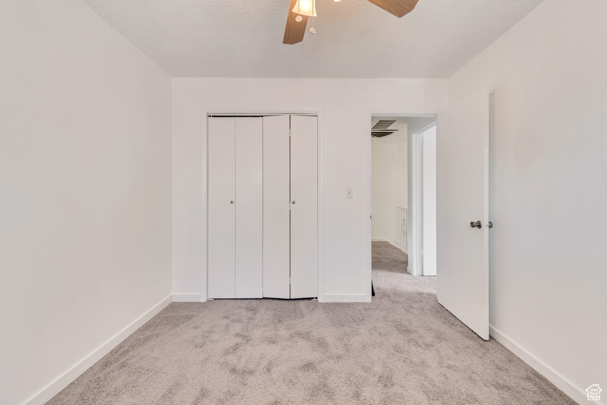 Unfurnished bedroom with a closet, a textured ceiling, and light colored carpet