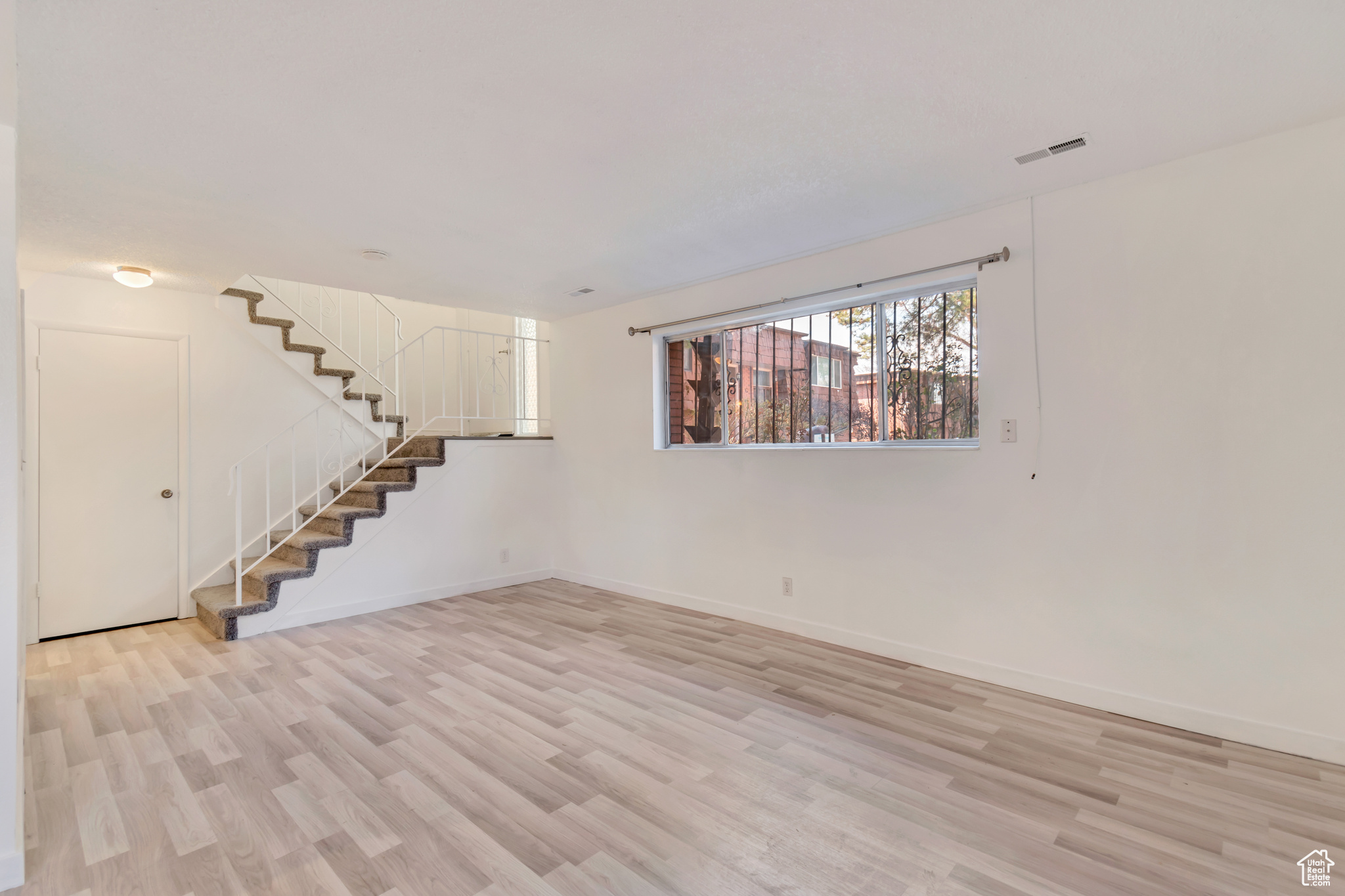 Interior space with light wood finished floors, stairway, visible vents, and baseboards