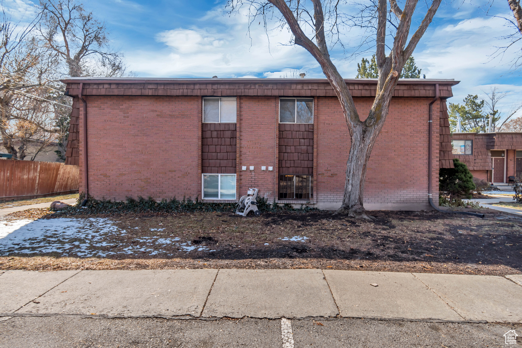 View of side of home with brick siding and fence