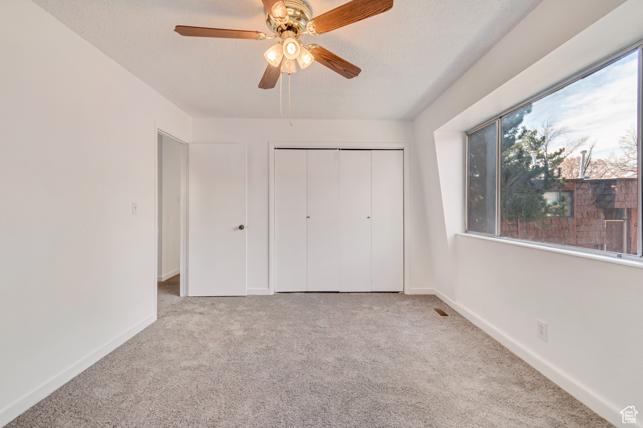 Unfurnished bedroom featuring light carpet, a textured ceiling, and baseboards