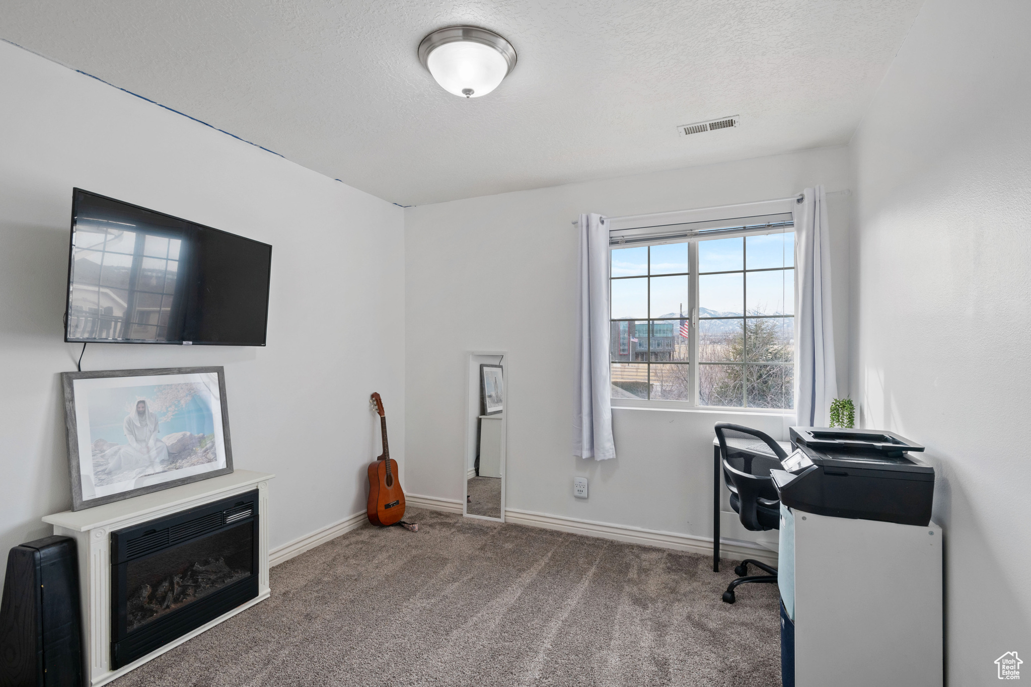 Carpeted office space featuring a textured ceiling, visible vents, and baseboards