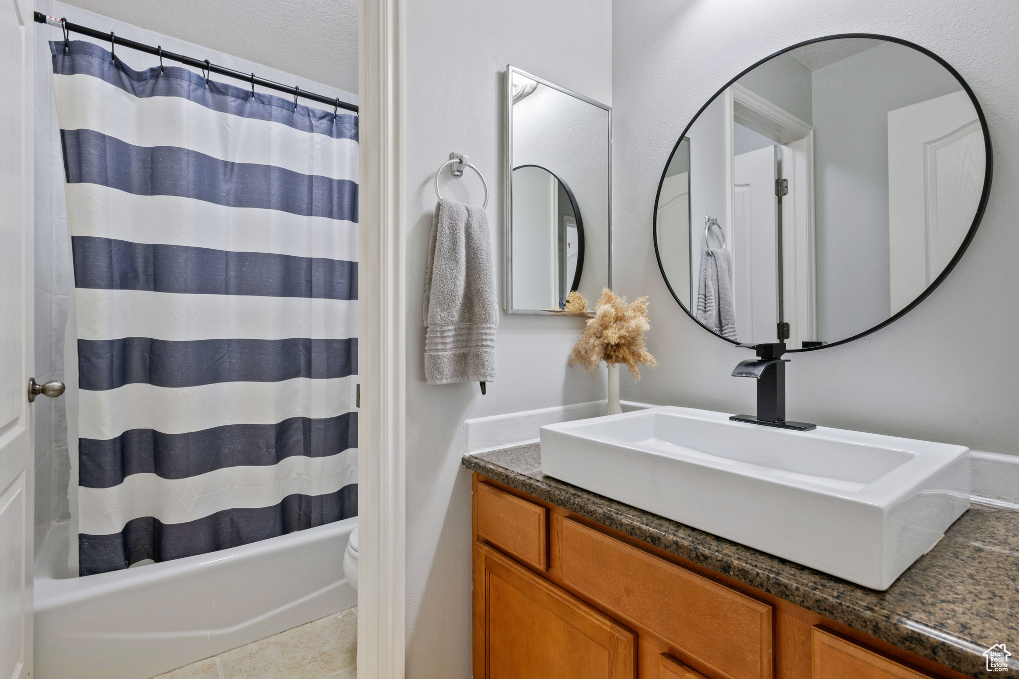 Bathroom with shower / bath combo, vanity, and toilet