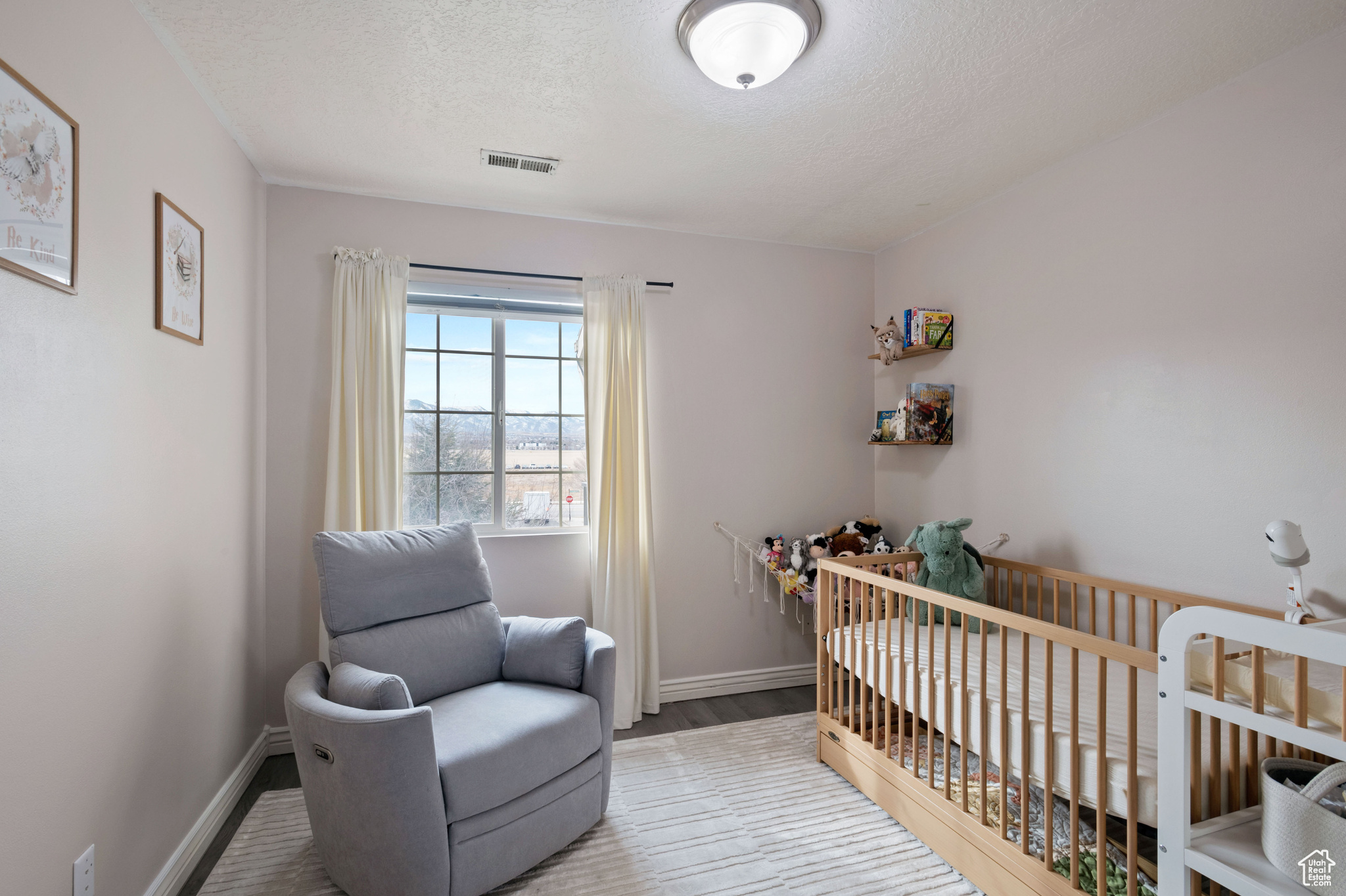 Bedroom with a crib, baseboards, visible vents, and wood finished floors
