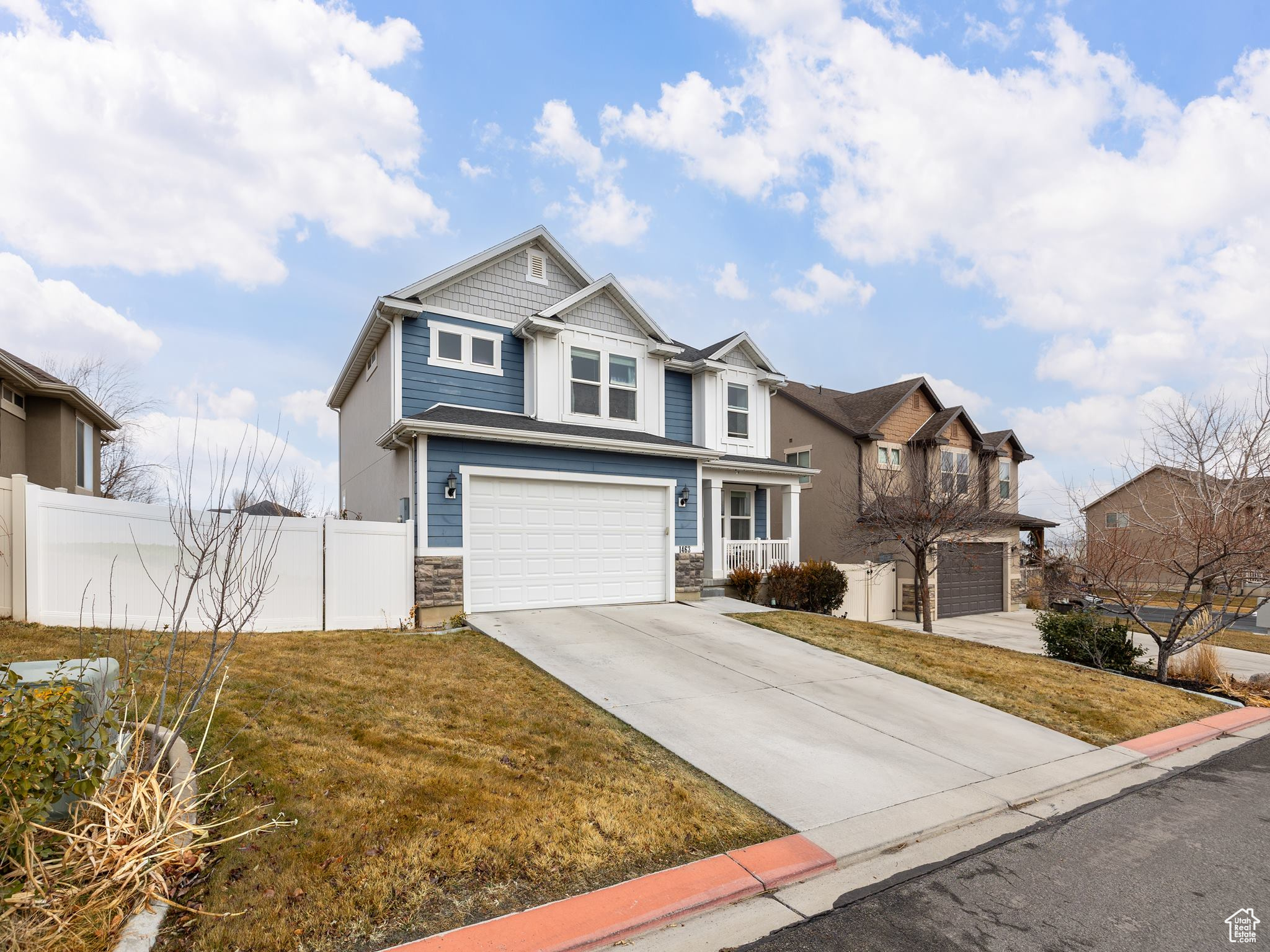 View of front of house featuring an attached garage, fence, concrete driveway, a residential view, and a front lawn