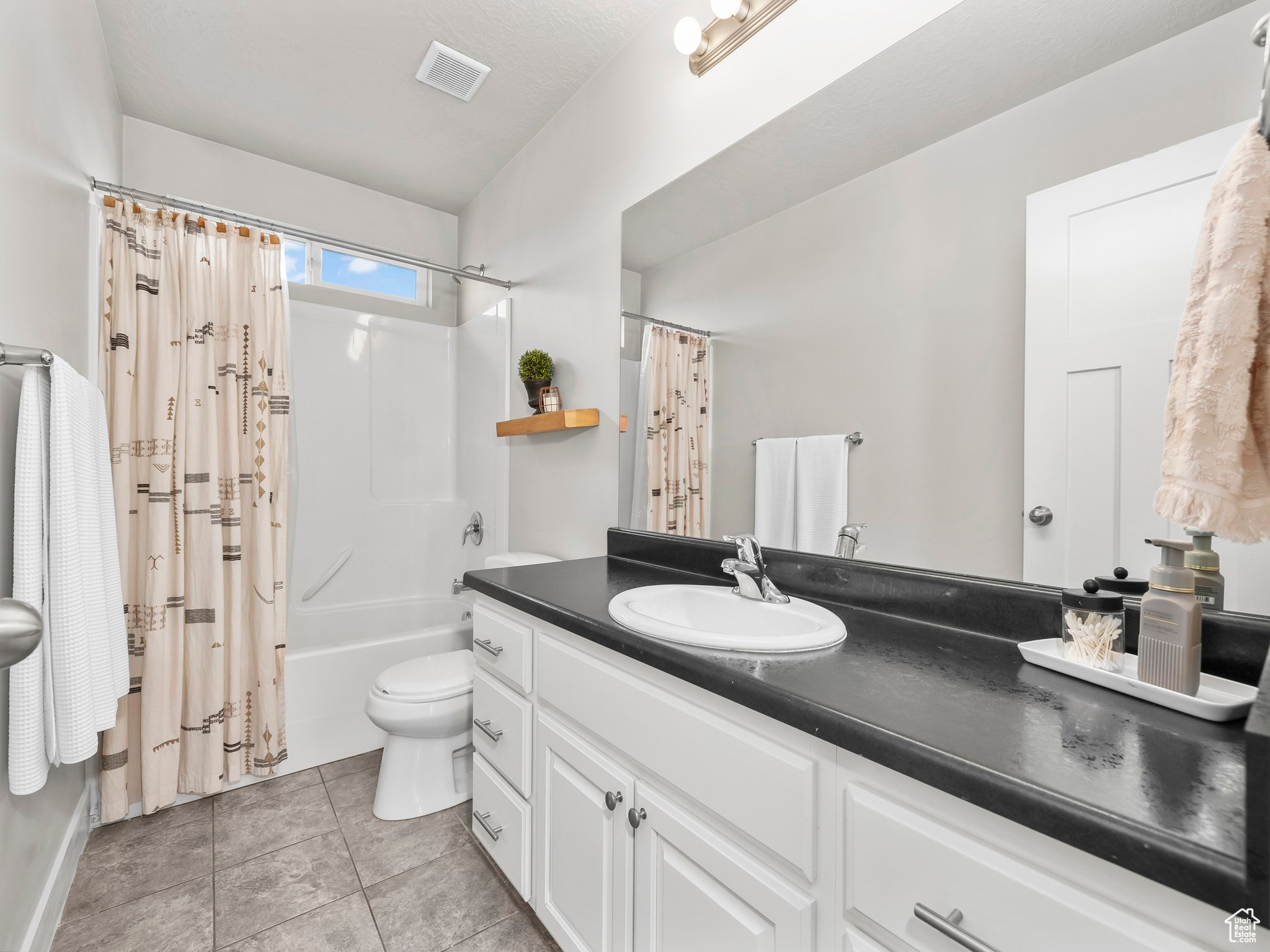 Bathroom featuring visible vents, toilet, tile patterned flooring, shower / bath combination with curtain, and vanity