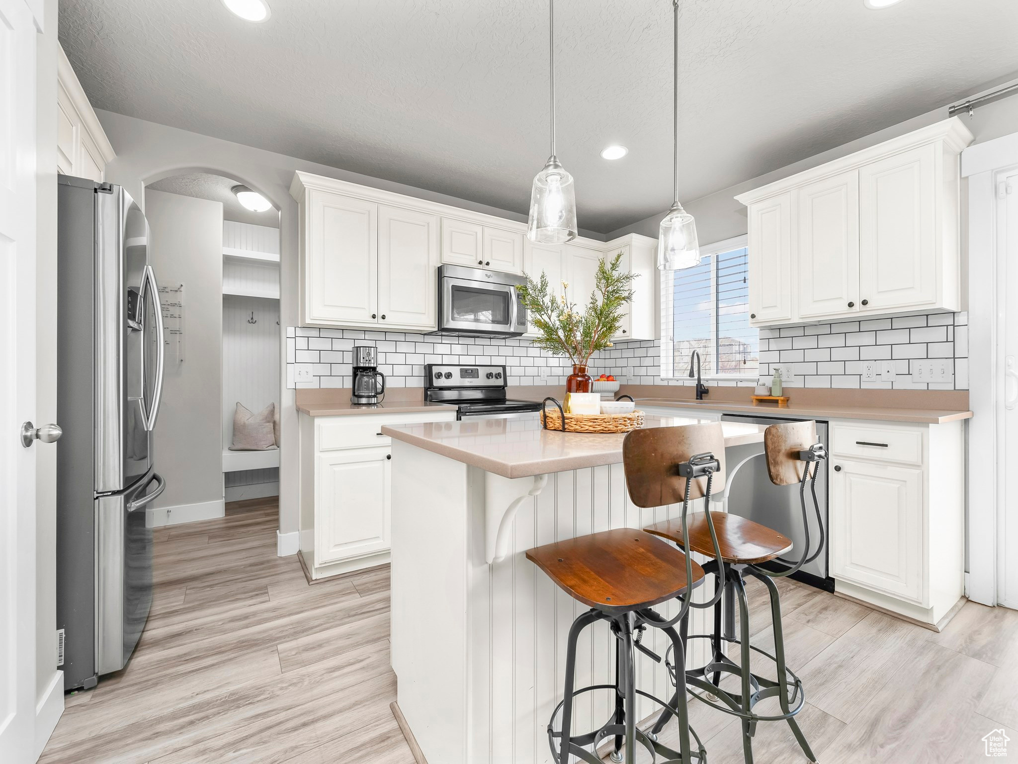 Kitchen with stainless steel appliances, a kitchen island, light countertops, and white cabinetry