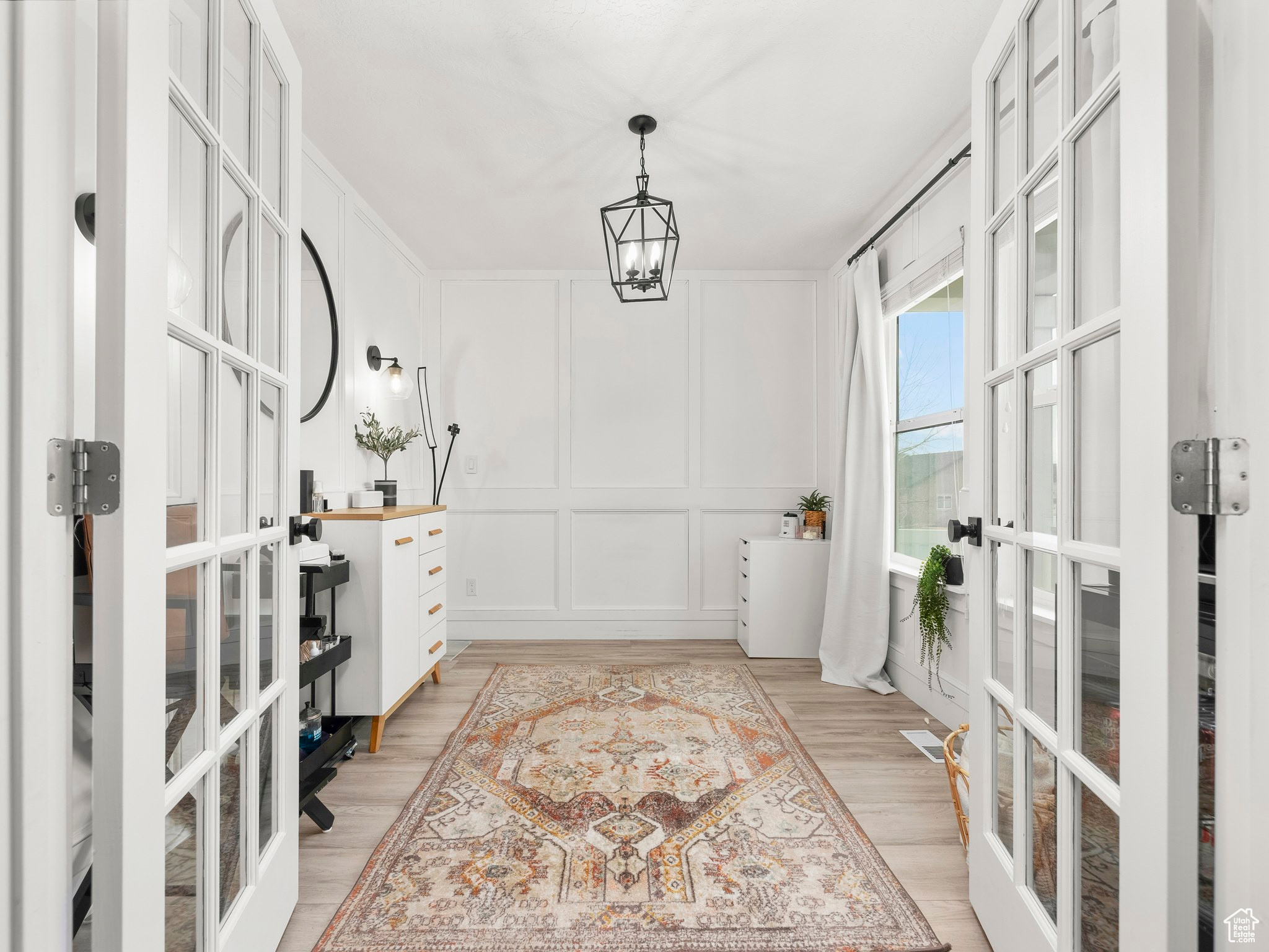 Interior space with visible vents, wood finished floors, an inviting chandelier, french doors, and a decorative wall