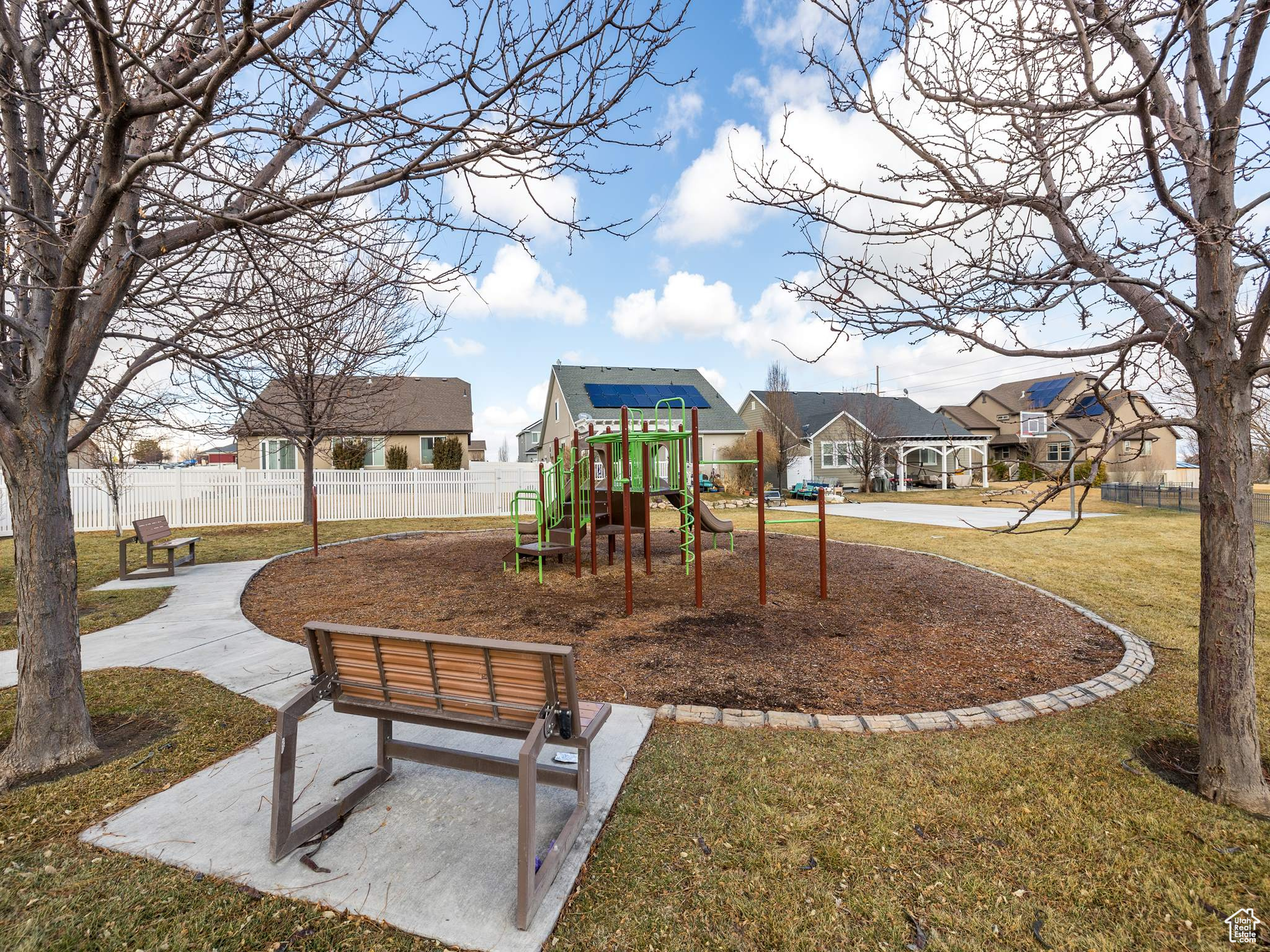 Community jungle gym with a residential view, fence, and a lawn