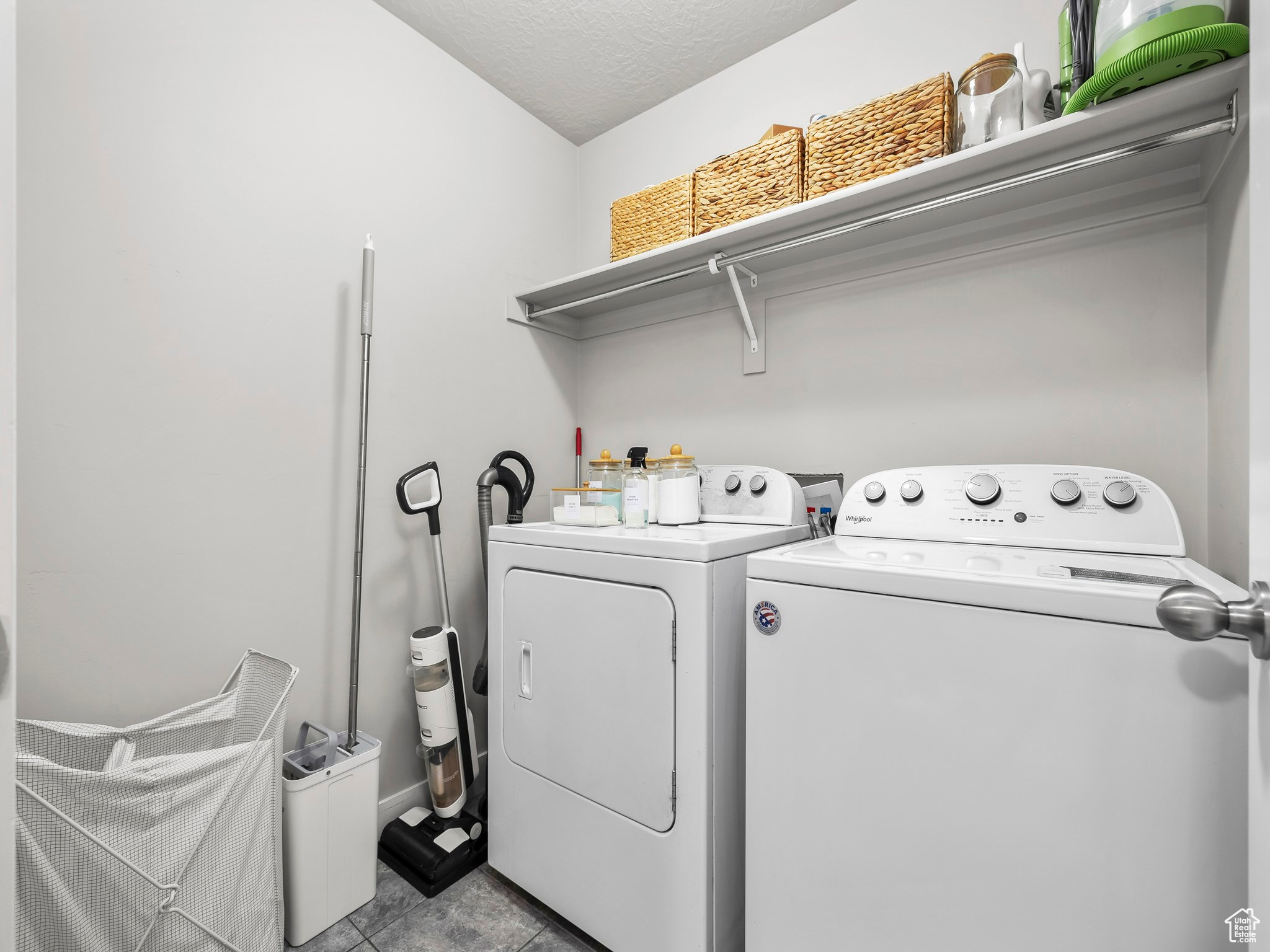 Clothes washing area featuring washing machine and dryer, laundry area, a textured ceiling, and light tile patterned floors