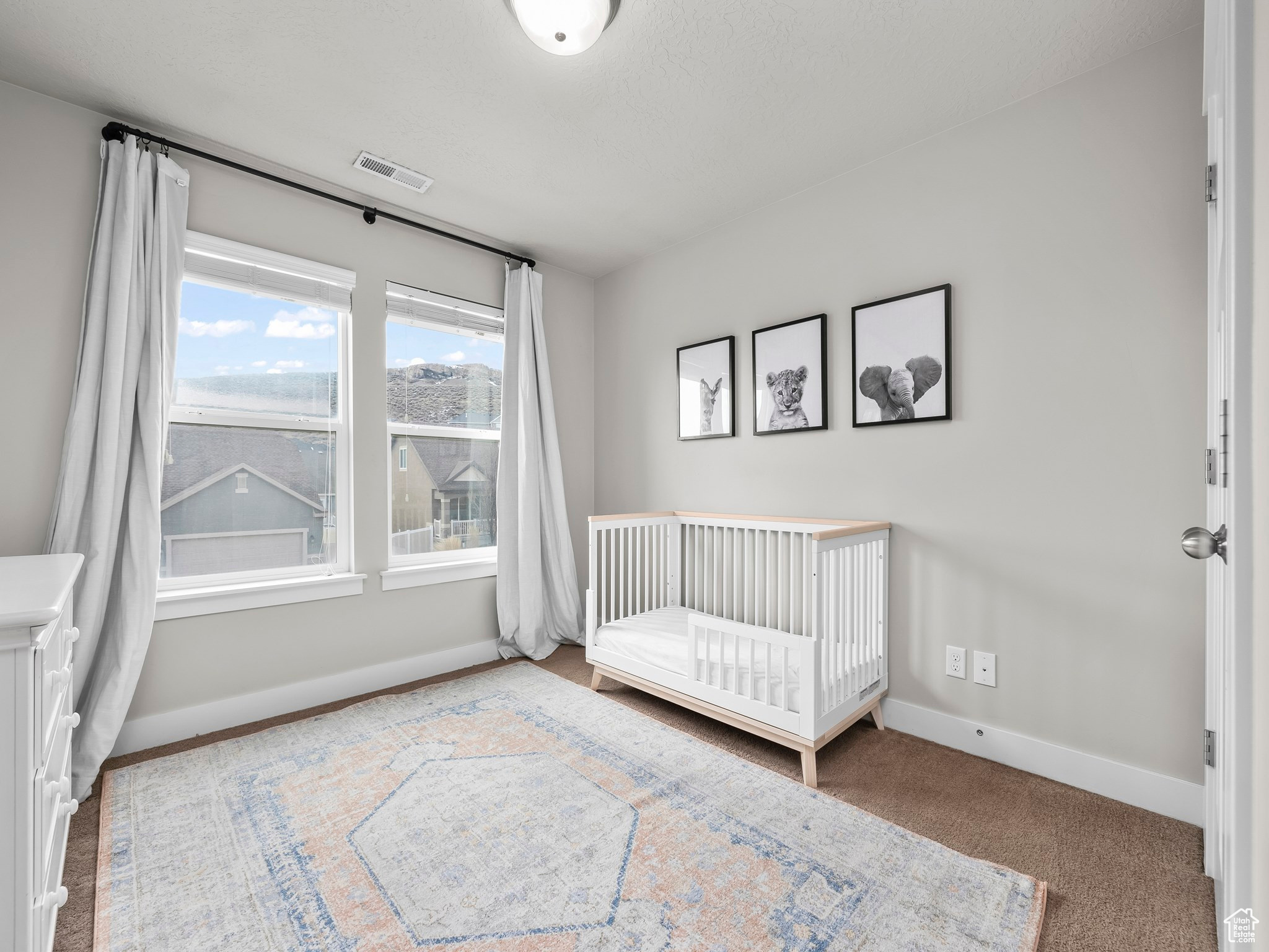 Unfurnished bedroom with carpet floors, a nursery area, visible vents, and baseboards