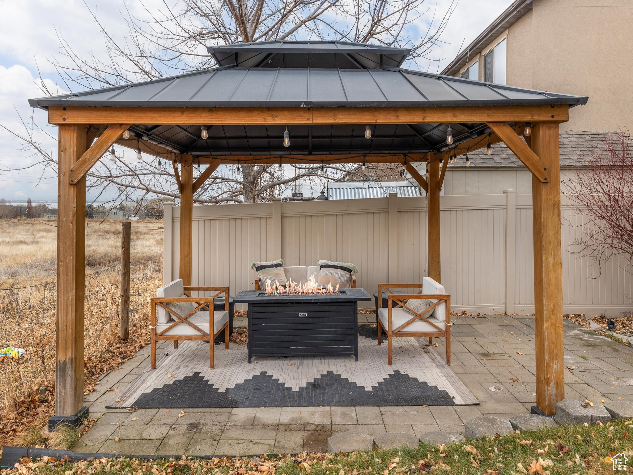 View of patio featuring an outdoor fire pit, fence, and a gazebo