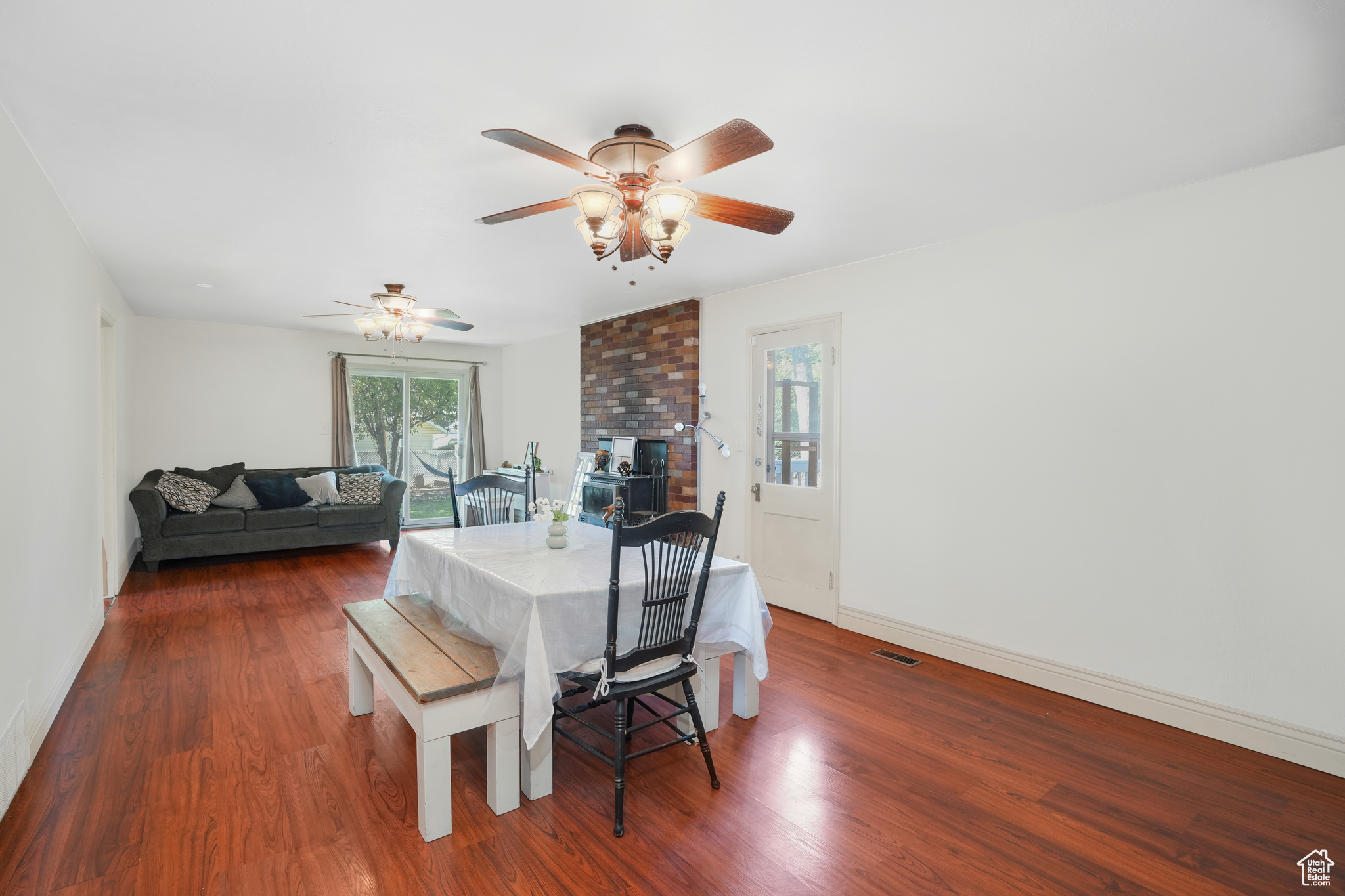 Dining room featuring a brick fireplace, dark wood finished floors, visible vents, and baseboards