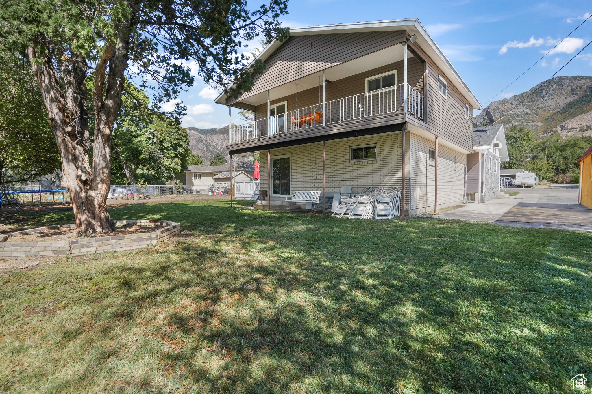 Back of property with a garage, a trampoline, a mountain view, and a lawn
