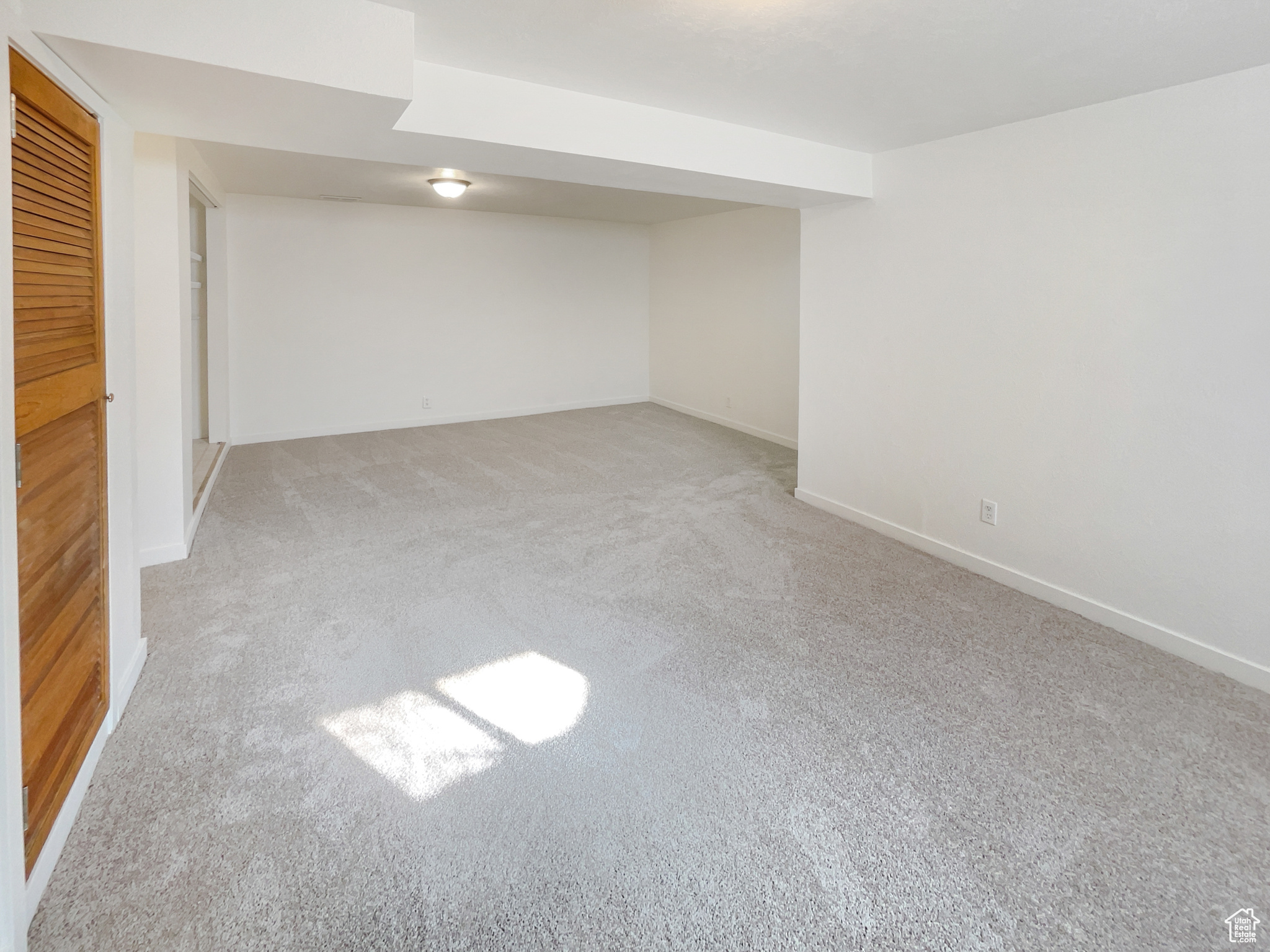 Finished below grade area featuring baseboards and light colored carpet
