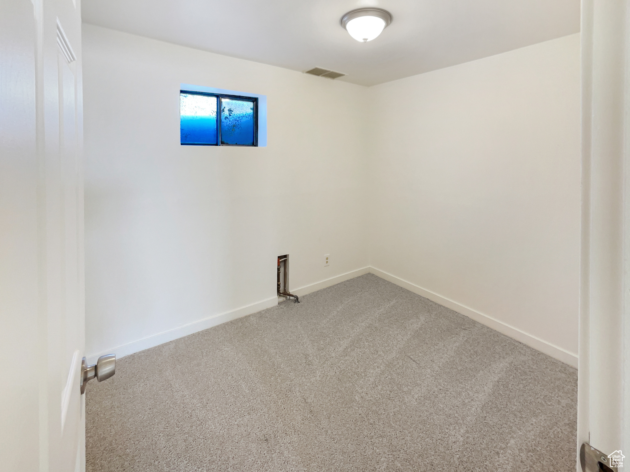 Spare room featuring carpet floors, visible vents, and baseboards