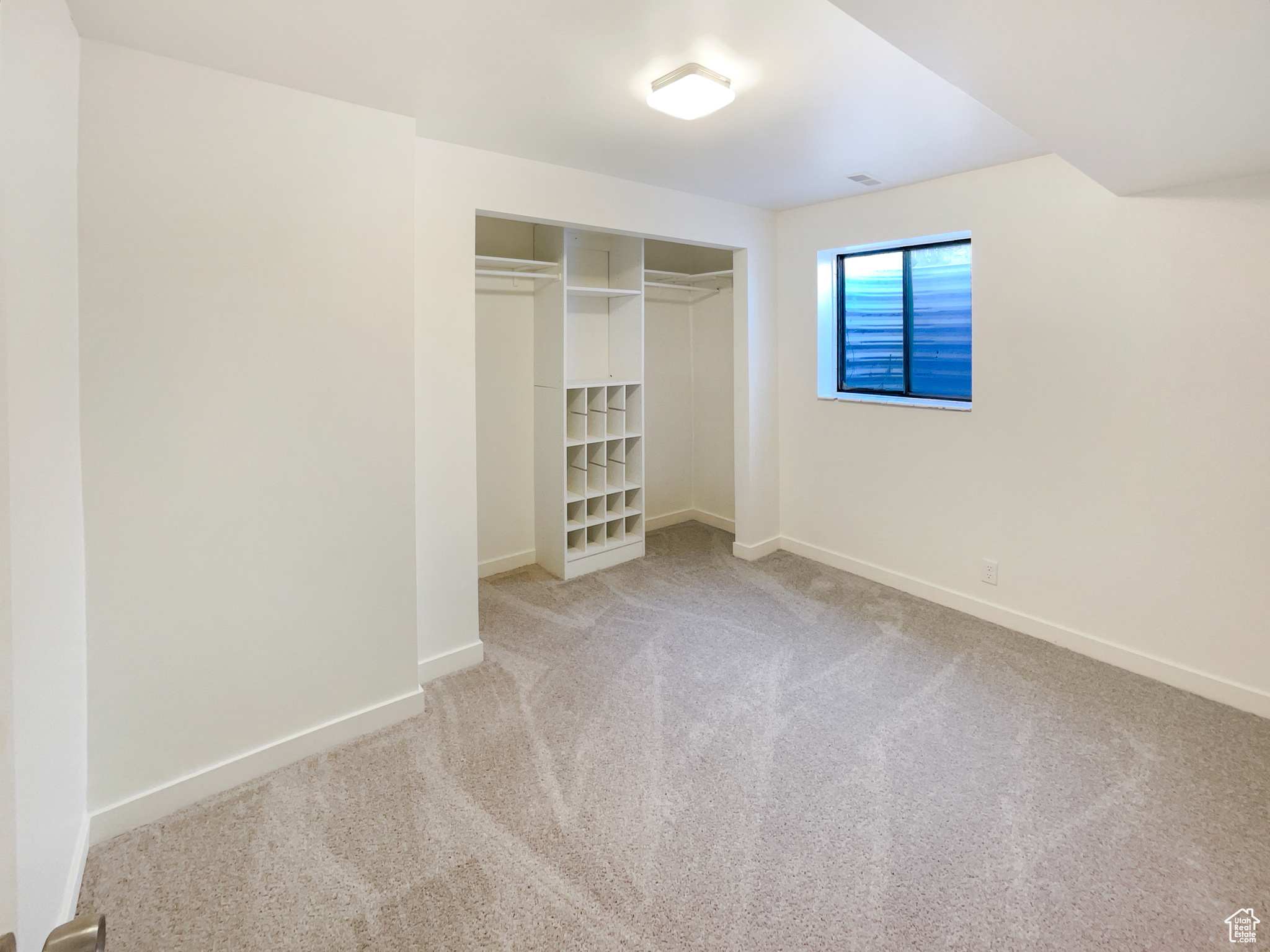 Unfurnished bedroom featuring a closet, light carpet, and baseboards