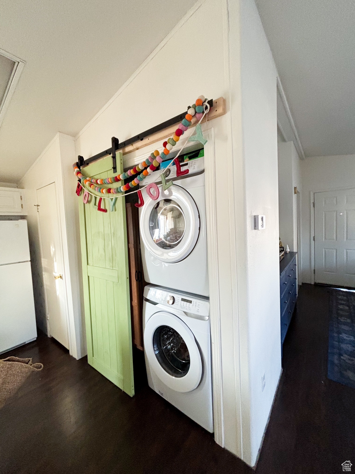 Laundry room featuring stacked washer and dryer, dark wood-style flooring, and laundry area