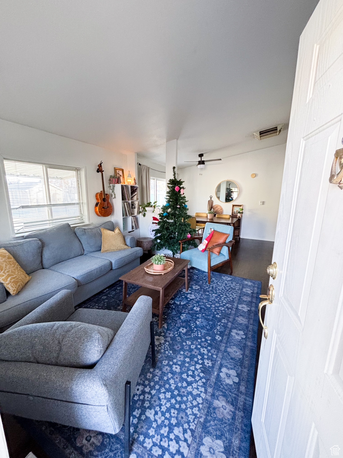Living area with ceiling fan, visible vents, and wood finished floors