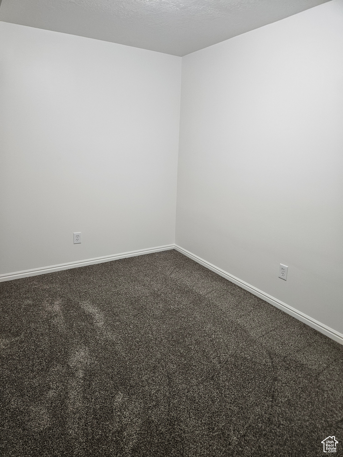 Carpeted empty room with baseboards and a textured ceiling