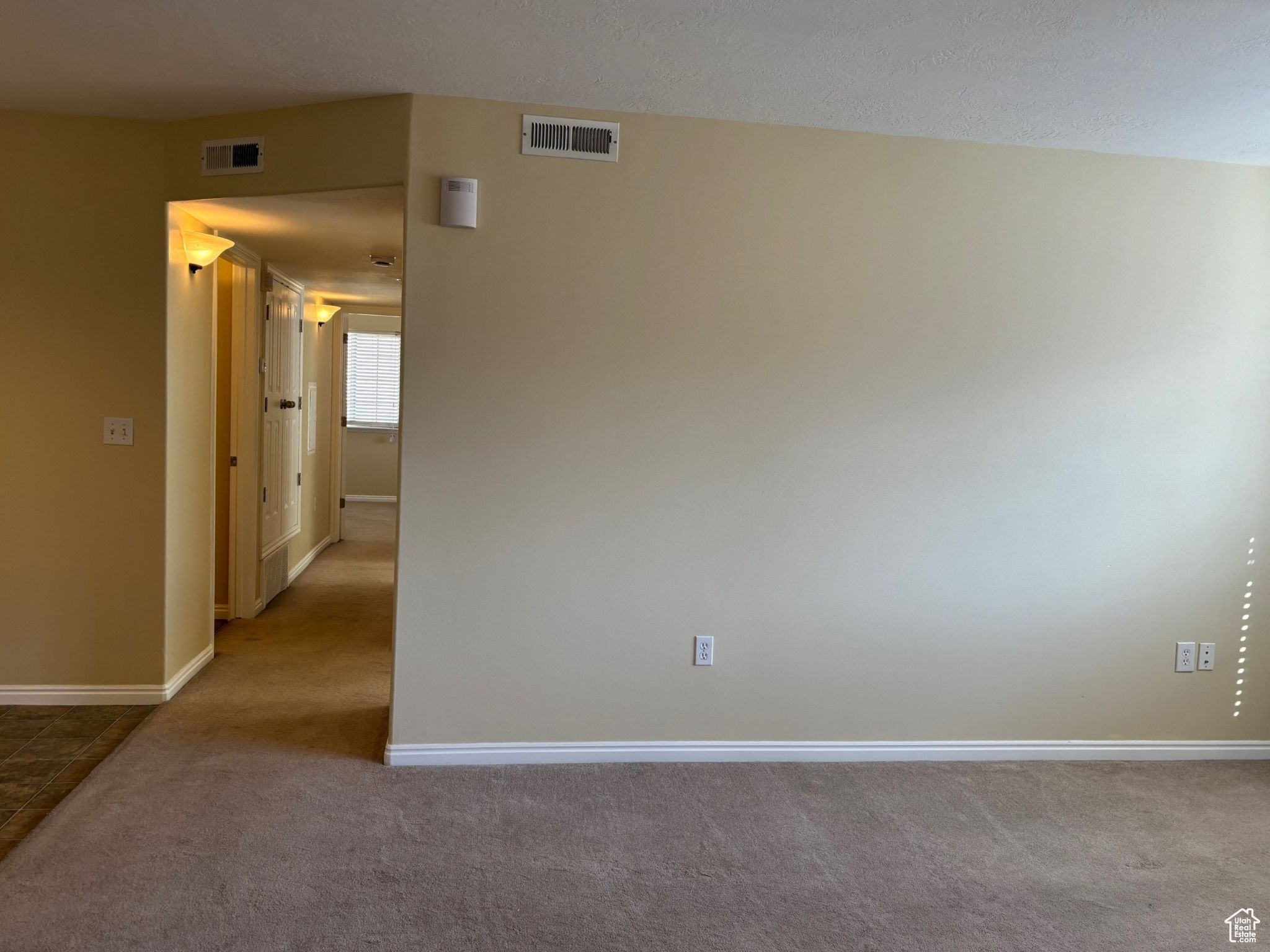 Unfurnished room with baseboards, visible vents, and light colored carpet