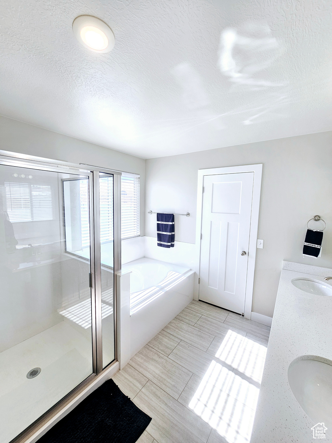 Bathroom with a sink, a shower stall, a textured ceiling, and a bath