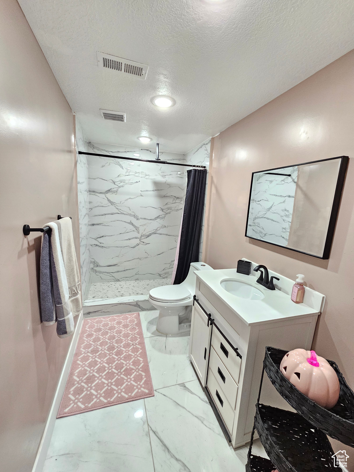 Full bathroom featuring a textured ceiling, marble finish floor, a stall shower, and visible vents