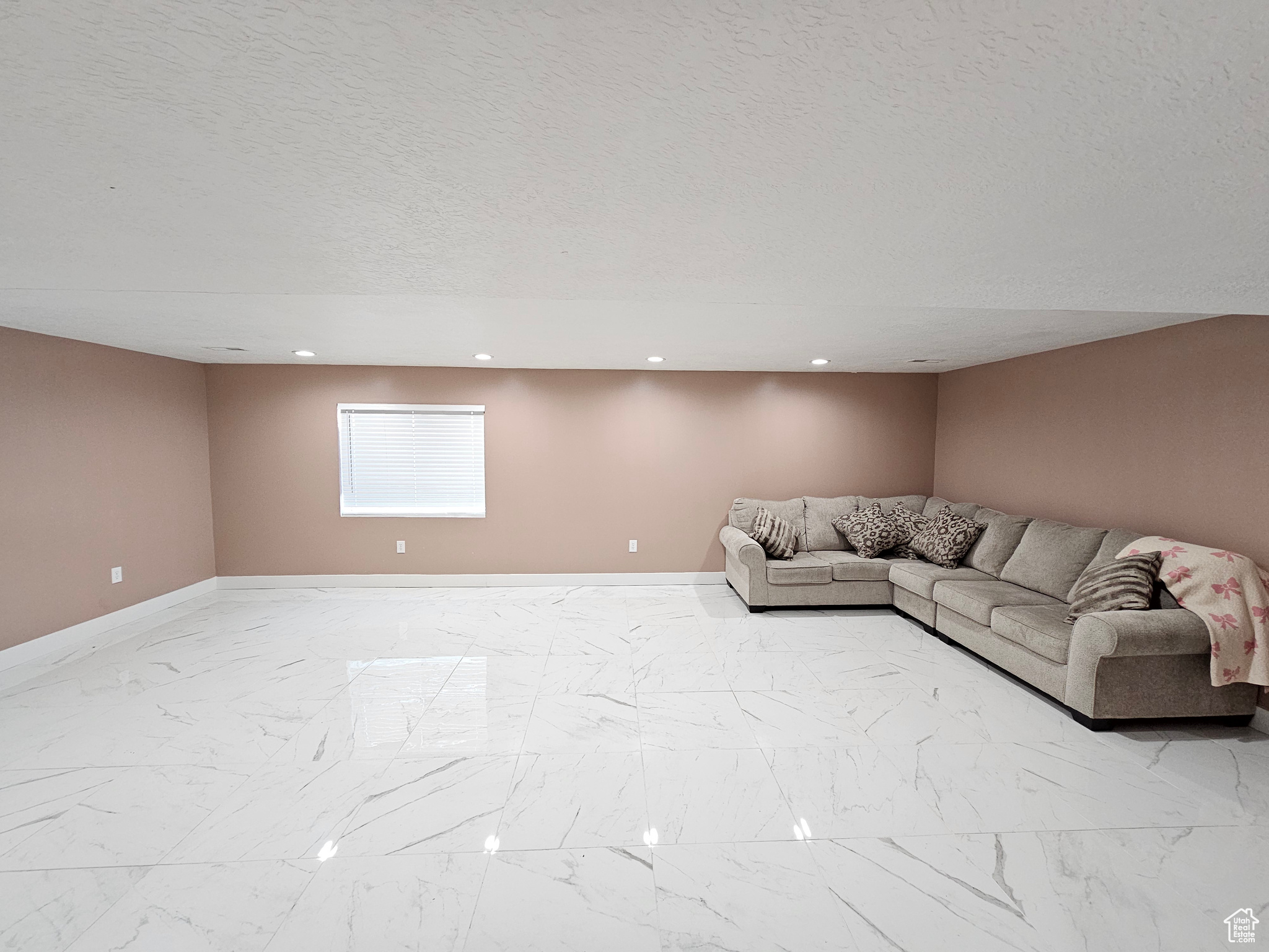 Unfurnished living room featuring a textured ceiling, marble finish floor, recessed lighting, and baseboards